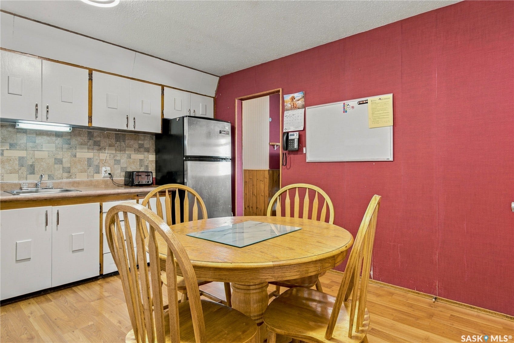 Kitchen area featuring wood-finish flooring, white cabinetry, and a tile backsplash