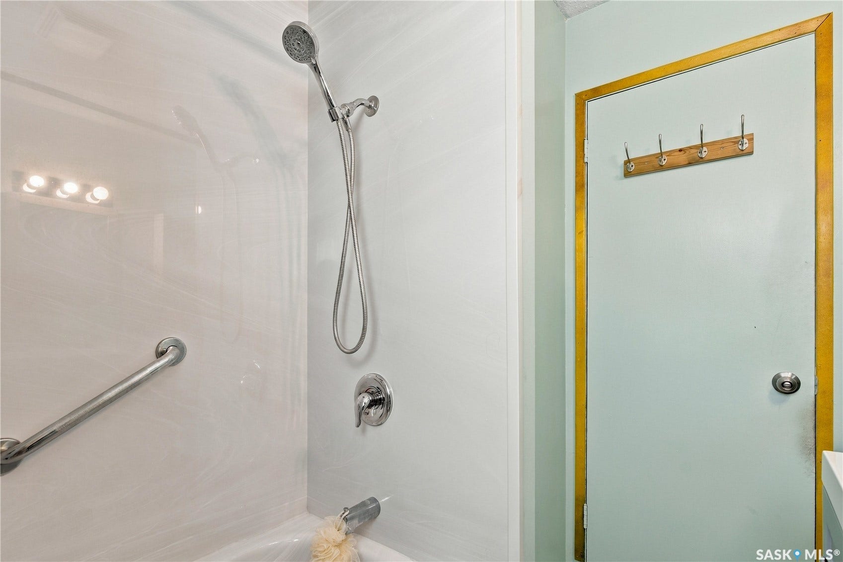 Bathtub shower with a chrome handheld showerhead and a wall-mounted grab bar