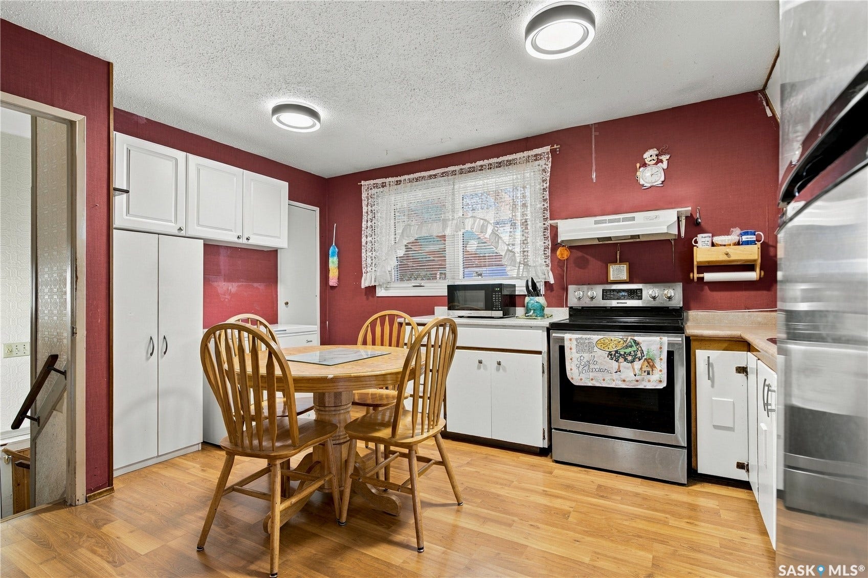 Wood-finish flooring, white cabinetry, stainless steel range, and multiple overhead light fixtures