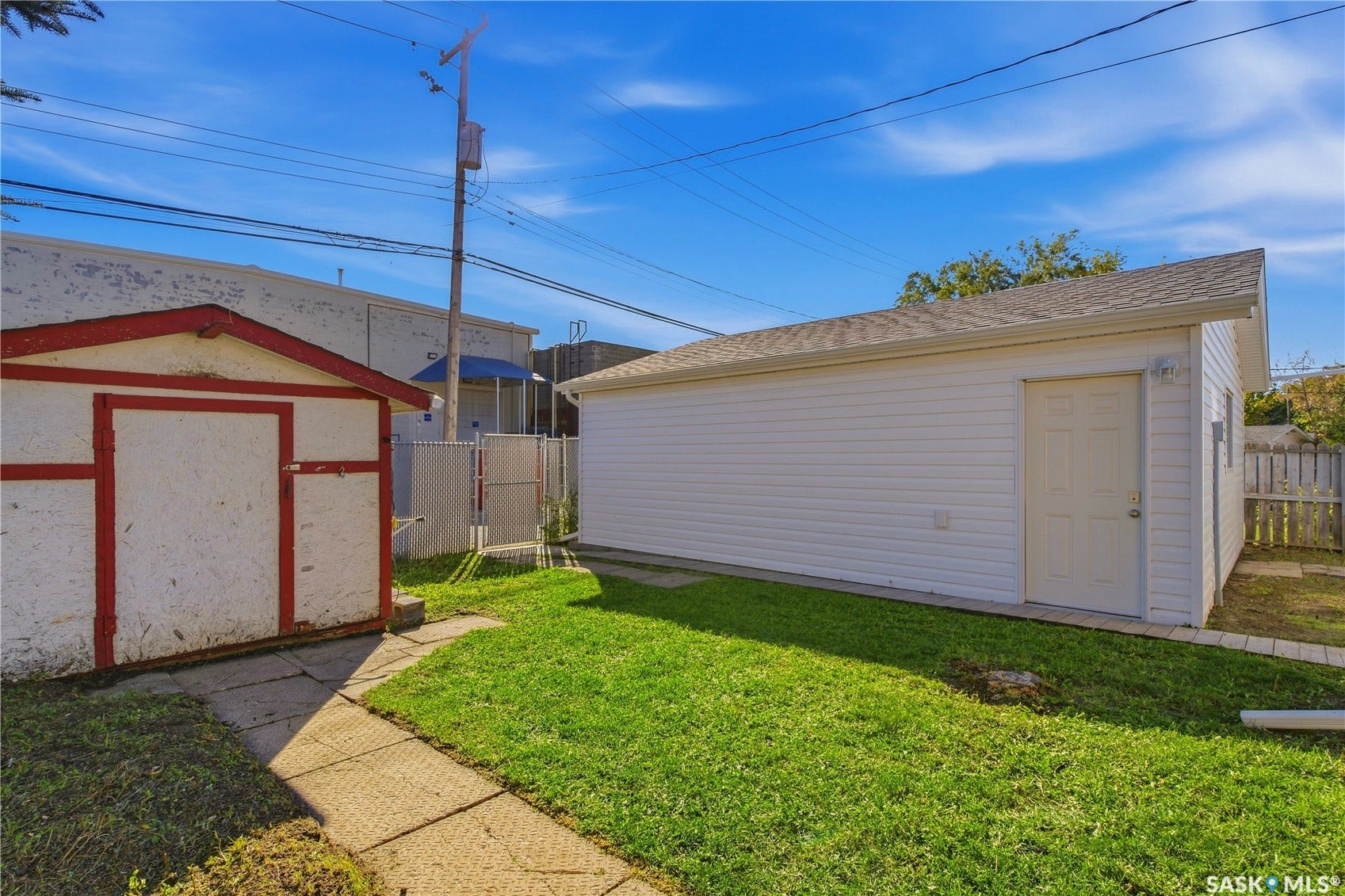 Detached garage with white siding, asphalt shingle roof, and a panel door