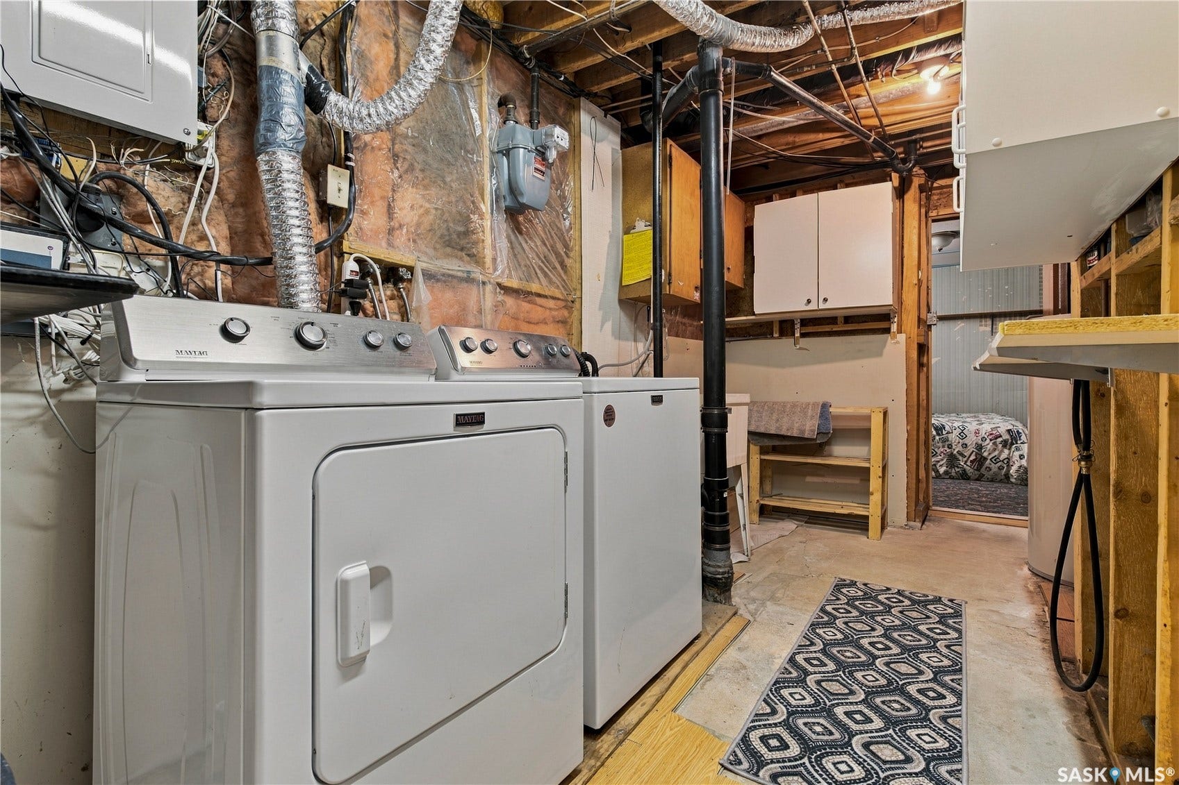 Utility space featuring a washer and dryer, built-in cabinetry, and exposed ceiling joists