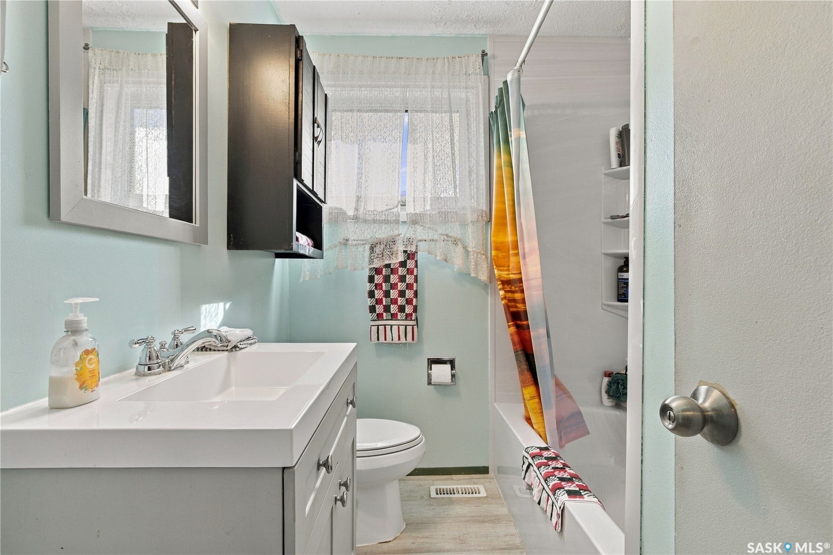 Vanity with integrated sink and chrome faucet, wall-mounted medicine cabinet, toilet, and bathtub with built-in shelving