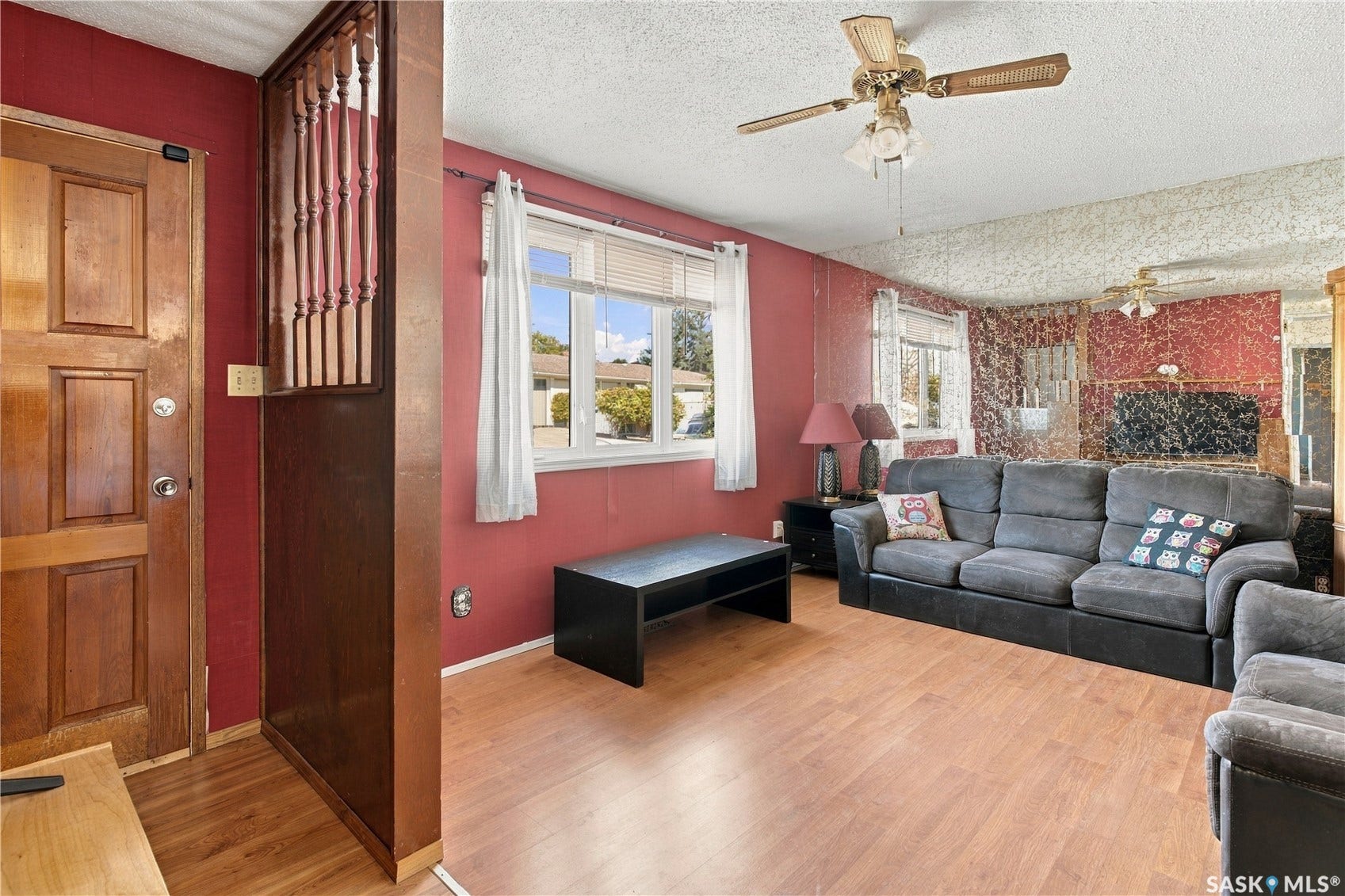 Wood-finish flooring throughout, ceiling fan with integrated lighting, and multiple windows providing natural illumination