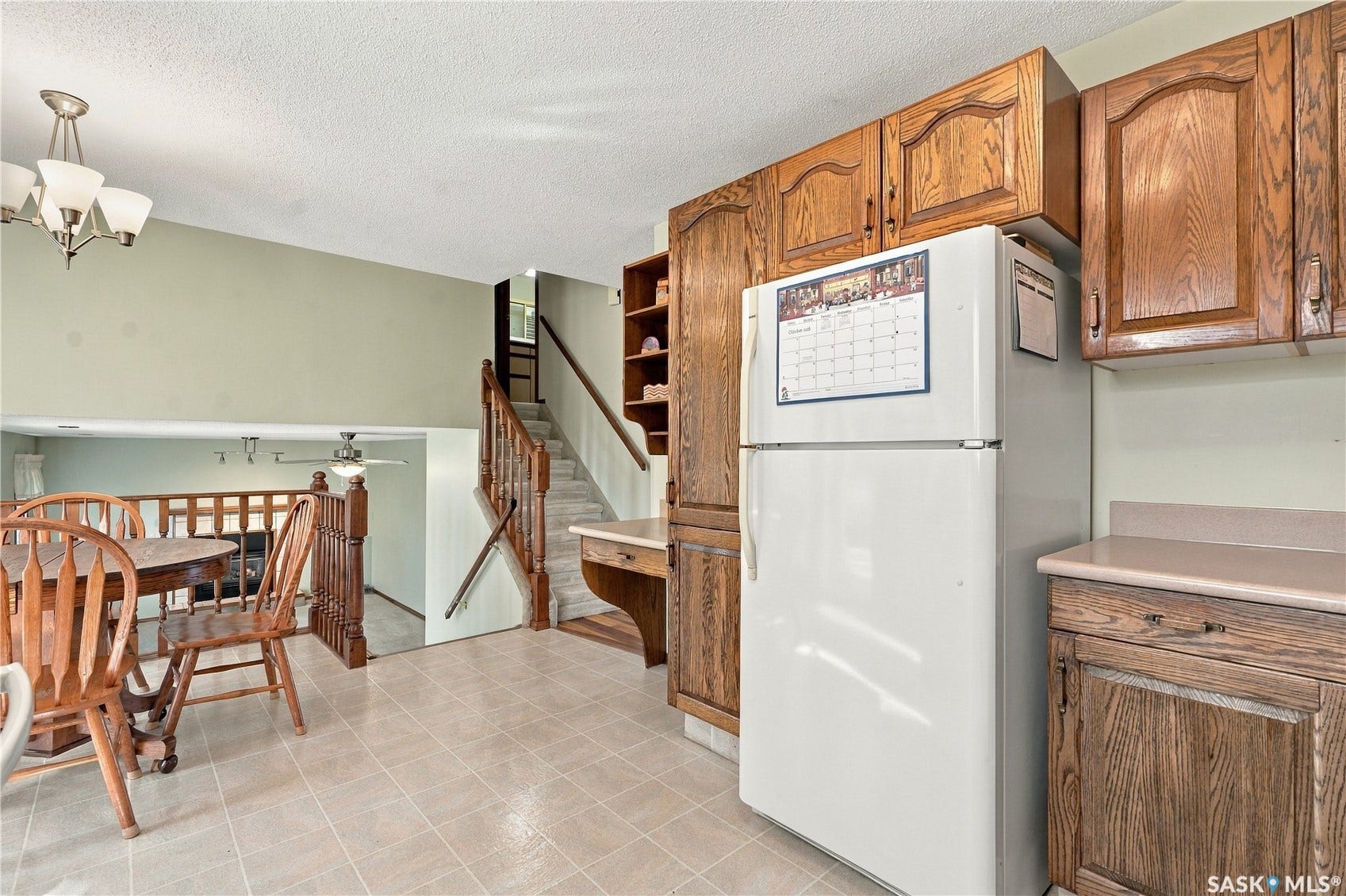 Kitchen featuring wood cabinetry, tiled flooring, and a white refrigerator