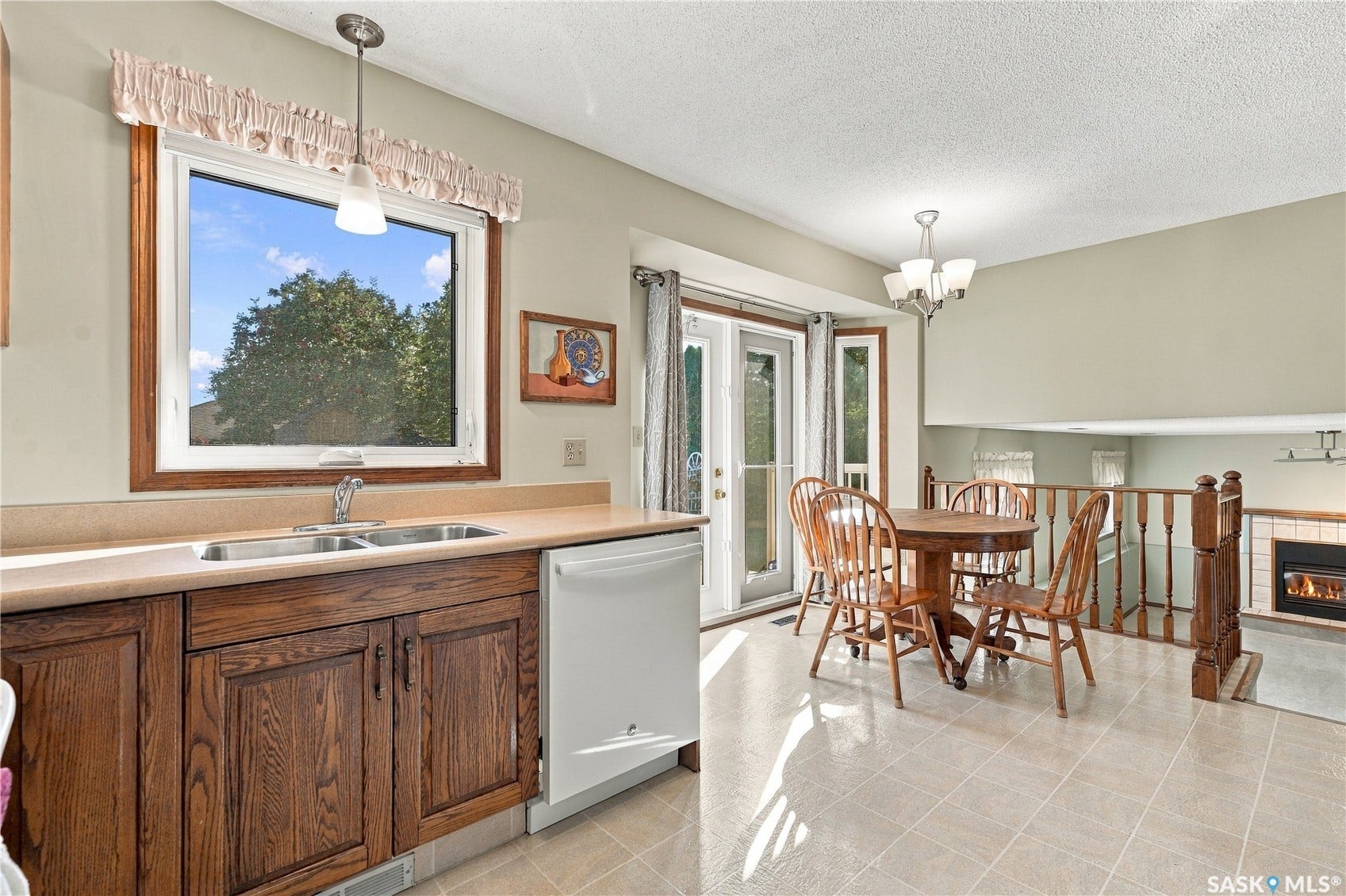 Eat-in kitchen featuring wood-finish cabinetry, a double basin sink, and a built-in dishwasher