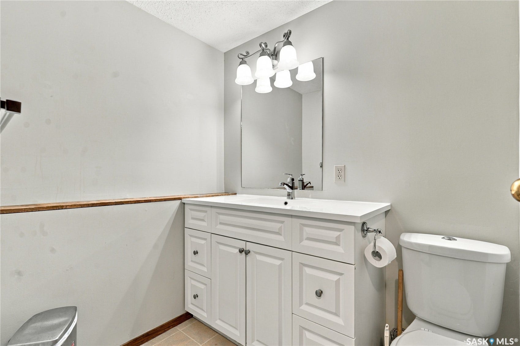 White vanity with shaker-style door and drawer fronts, chrome hardware, integrated sink, and wall-mounted mirror