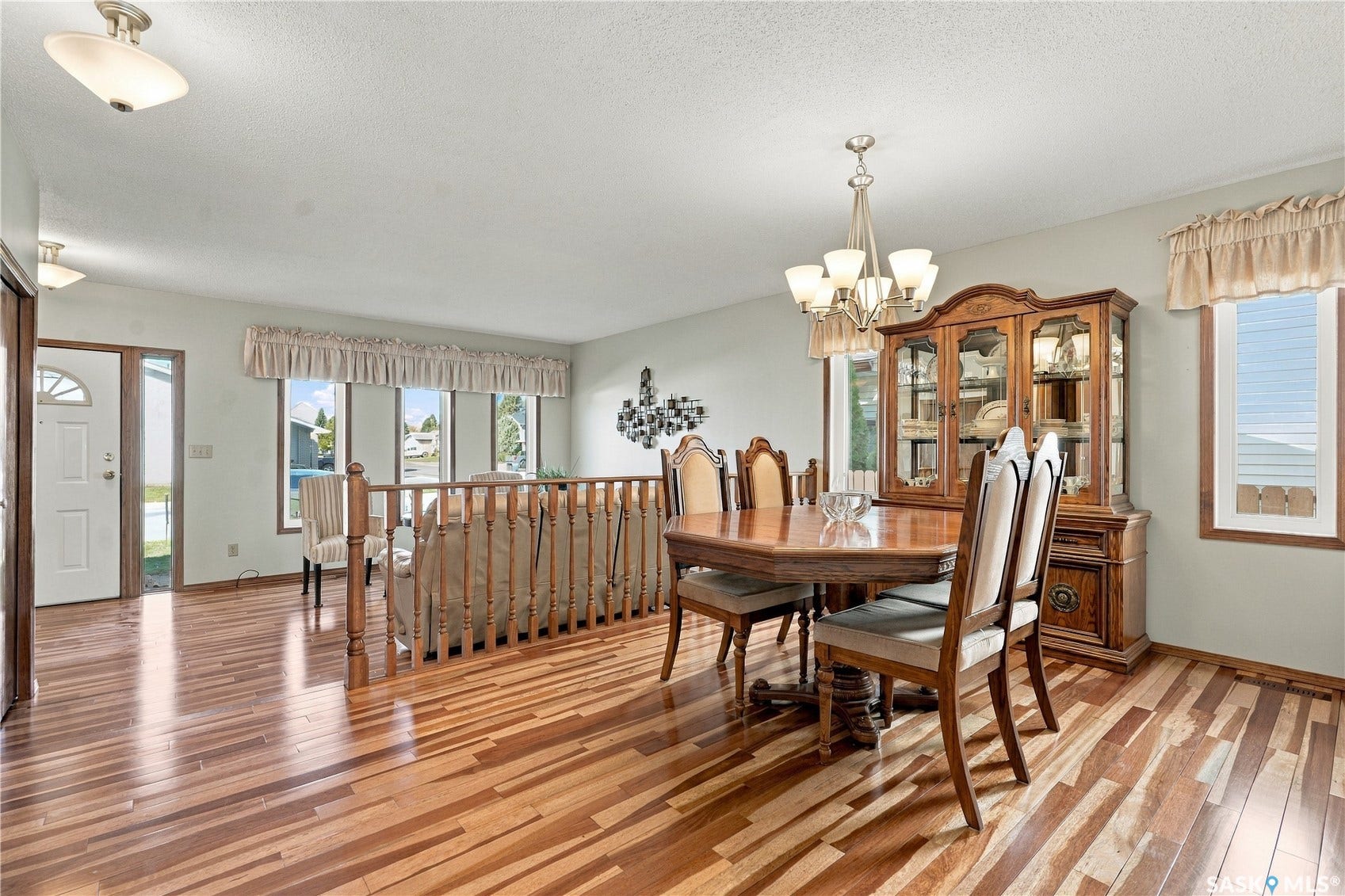 Wood-finish flooring, multiple windows, a decorative chandelier, and a built-in wood hutch