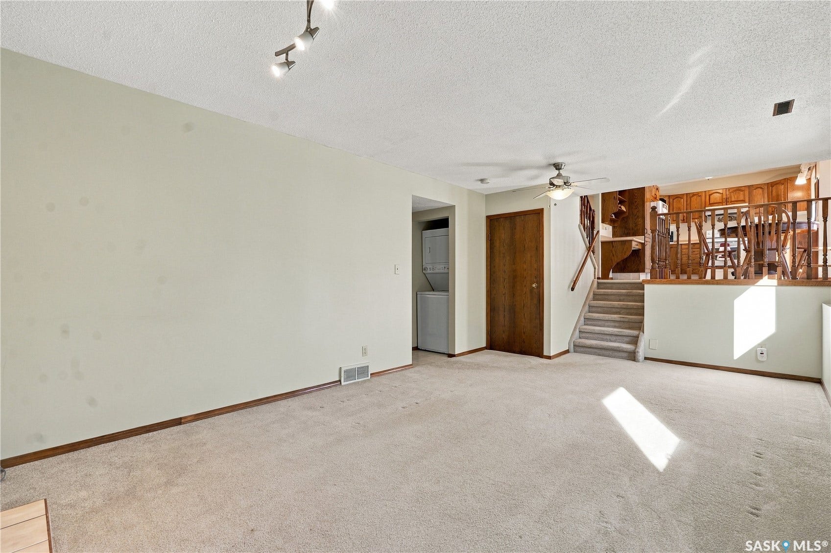 Carpeted flooring throughout, track lighting, ceiling fan, wood-finish doors, and a built-in stacked washer and dryer