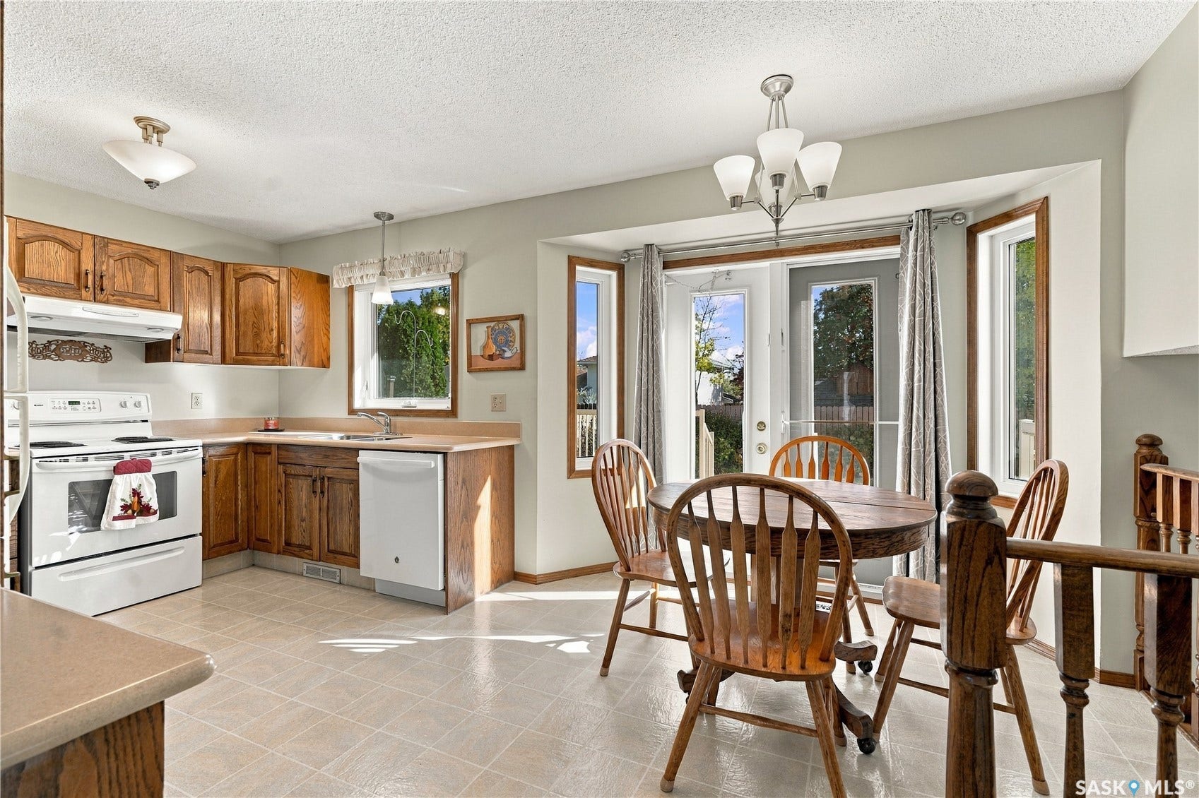 Kitchen featuring wood cabinetry, white appliances, and tiled flooring