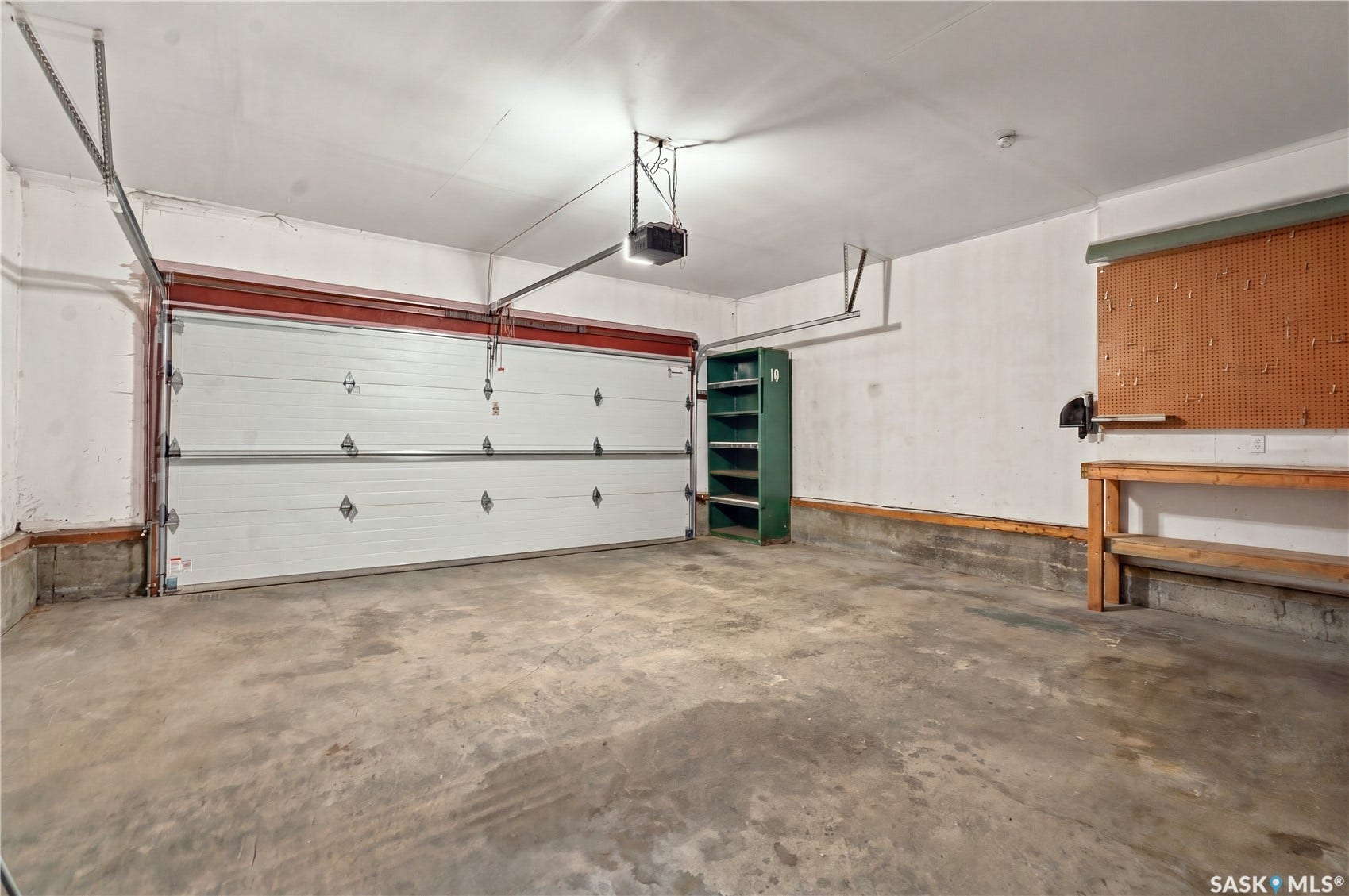 Attached two-car garage with concrete flooring, automatic garage door opener, and built-in workbench