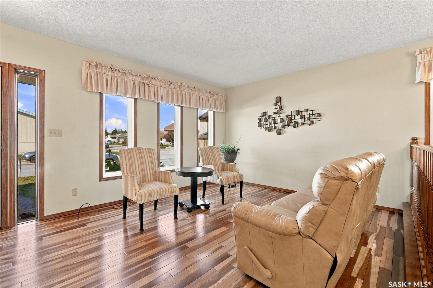 Wood-finish flooring, multiple windows providing natural light, and a wood railing system
