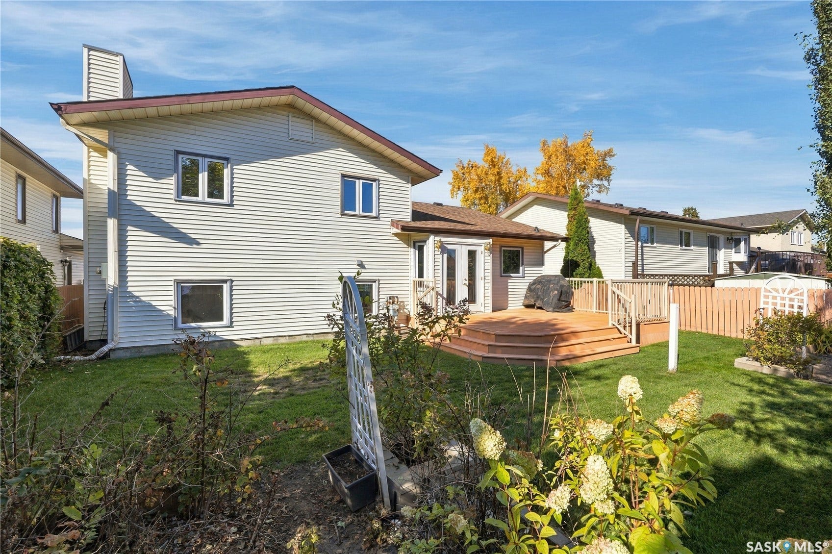 Spacious backyard featuring a multi-level wood deck, manicured lawn, and perimeter fencing
