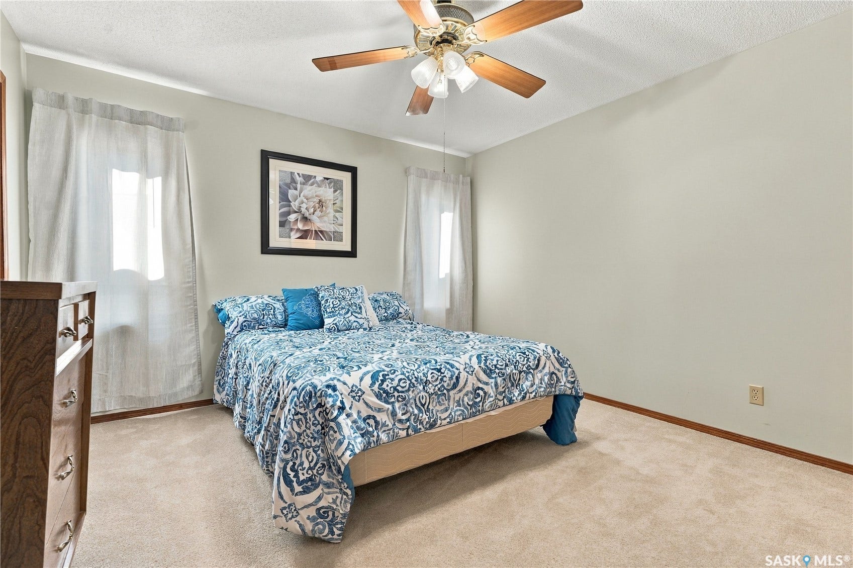 Carpeted flooring with a ceiling fan and two windows