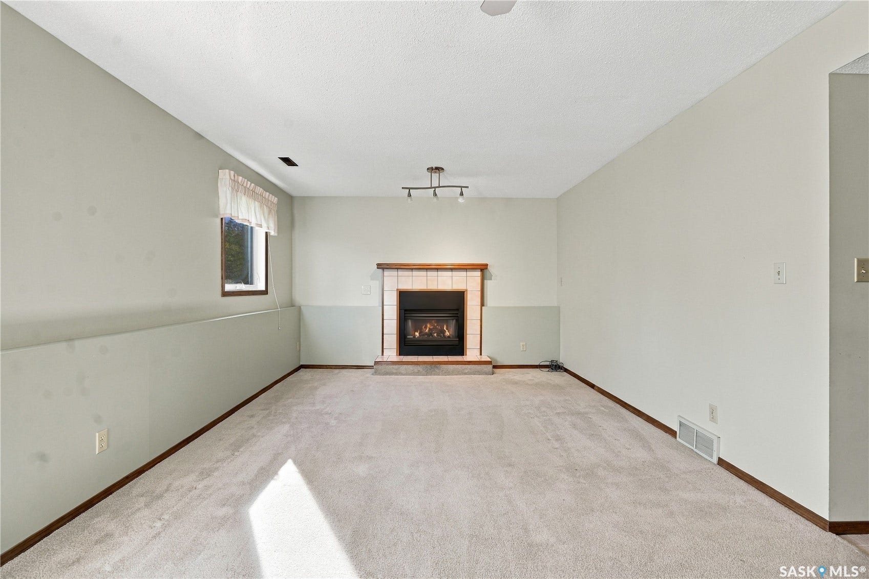 Carpeted flooring complemented by a fireplace with a tiled surround and hearth