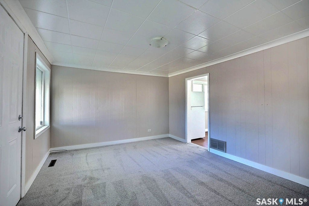 Neutral tone wall paneling with white trim, new carpet flooring, and a flush mount ceiling light fixture