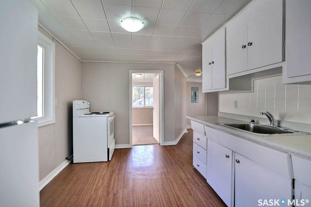 Kitchen with wood-finish flooring, white cabinetry, and white countertops