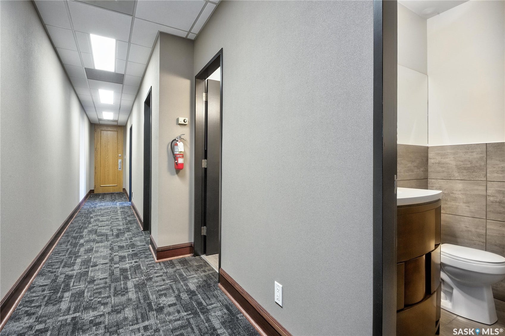 Hallway featuring recessed ceiling lights, patterned carpet, wood-finish base trim, and interior doors