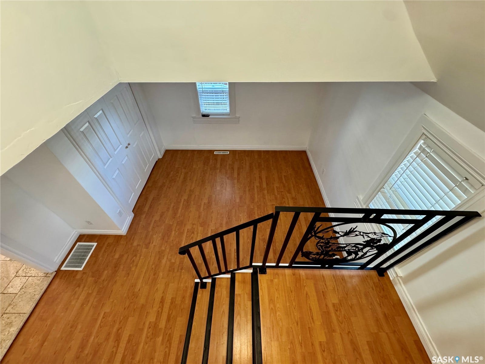 365 Keats Street, Southey SK S0G 4P0 Hardwood-finish flooring, built-in bi-fold closet, window with horizontal blinds, decorative metal stair railing, and tiled flooring
