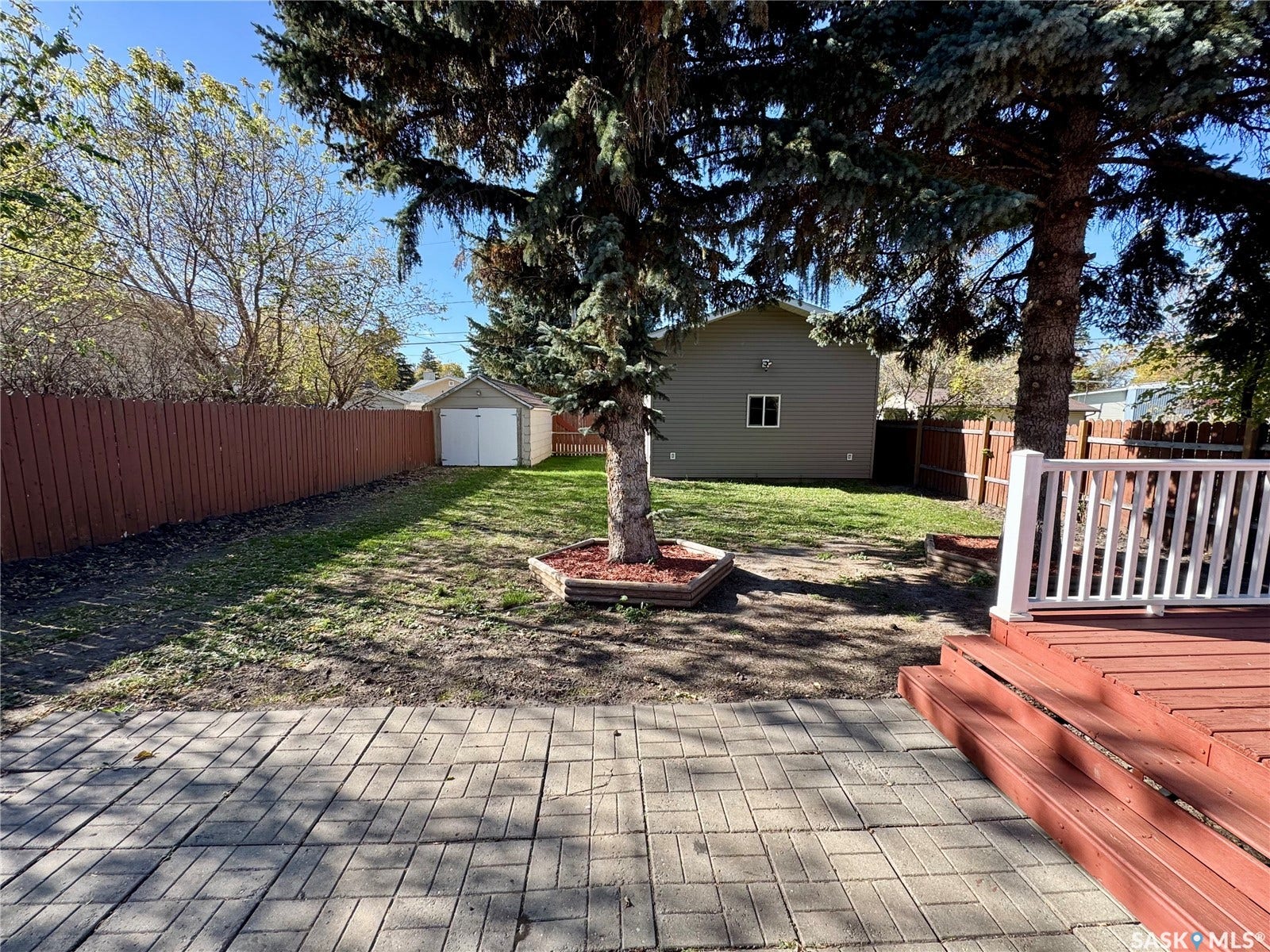 365 Keats Street, Southey SK S0G 4P0 Expansive backyard featuring a stained wood deck, brick paver patio, fenced perimeter, and detached accessory structure