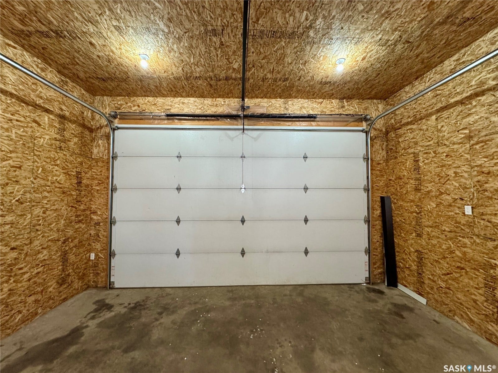 365 Keats Street, Southey SK S0G 4P0 Garage featuring an overhead door, exposed wood-finish walls and ceiling, and two ceiling-mounted light fixtures