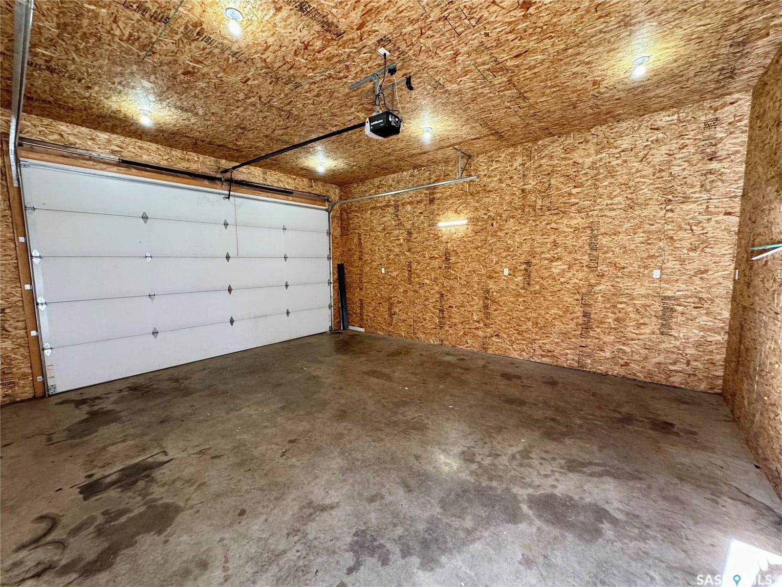 365 Keats Street, Southey SK S0G 4P0 Single garage door with automatic opener, concrete flooring, and durable paneling on walls and ceiling