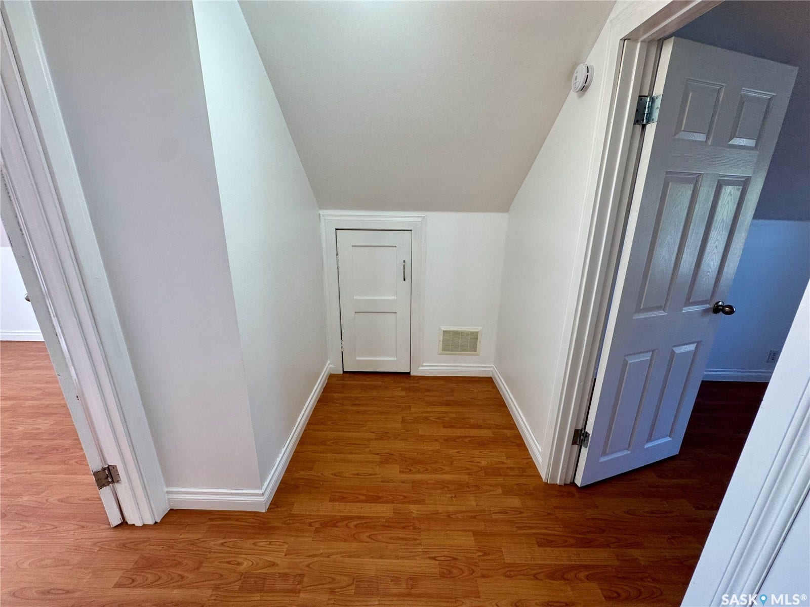 365 Keats Street, Southey SK S0G 4P0 Wood-finish flooring with white trim, white paneled doors, and angled walls