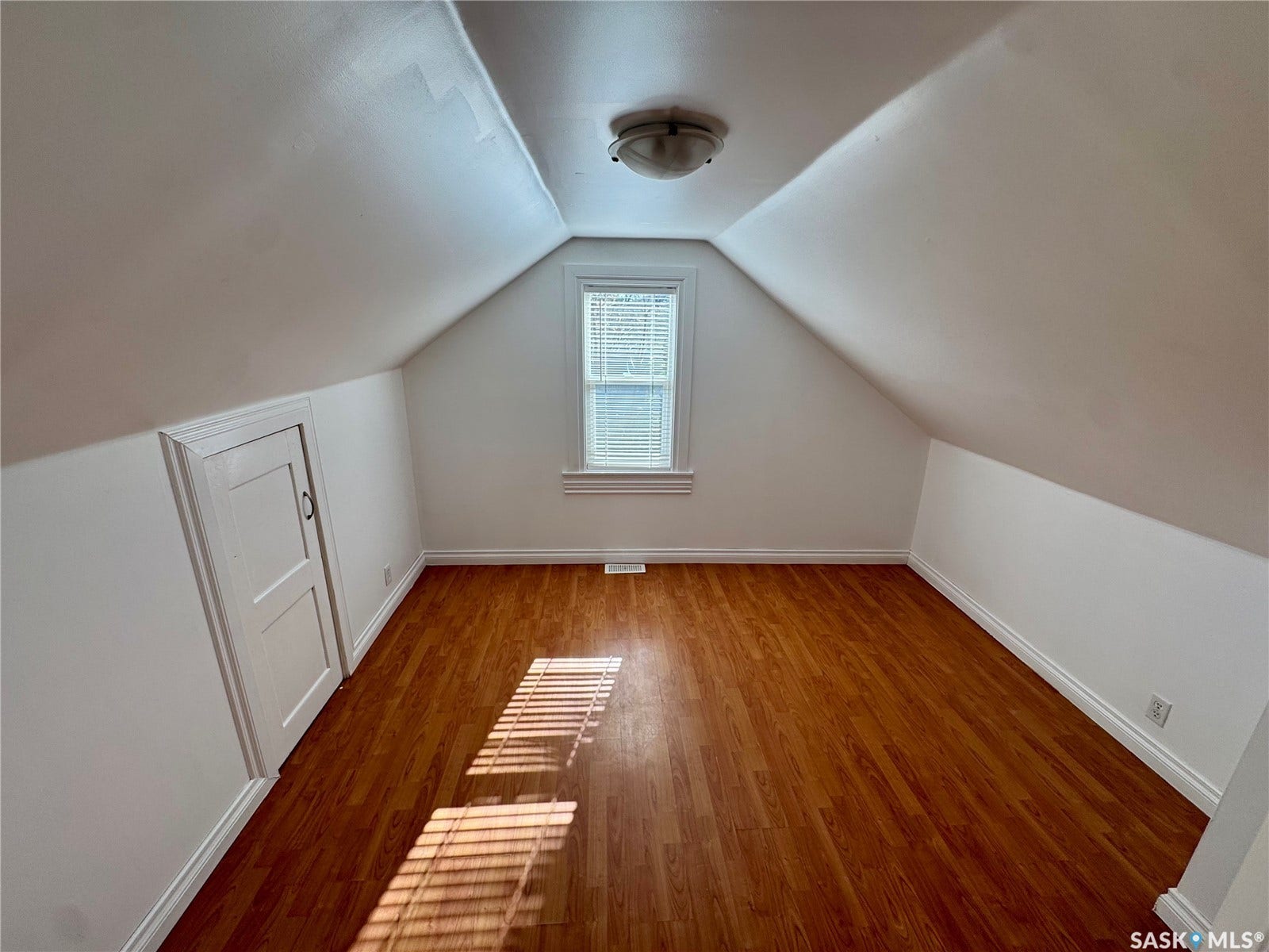 365 Keats Street, Southey SK S0G 4P0 Angled white walls with a window, wood-finish flooring, and a flush mount ceiling light fixture
