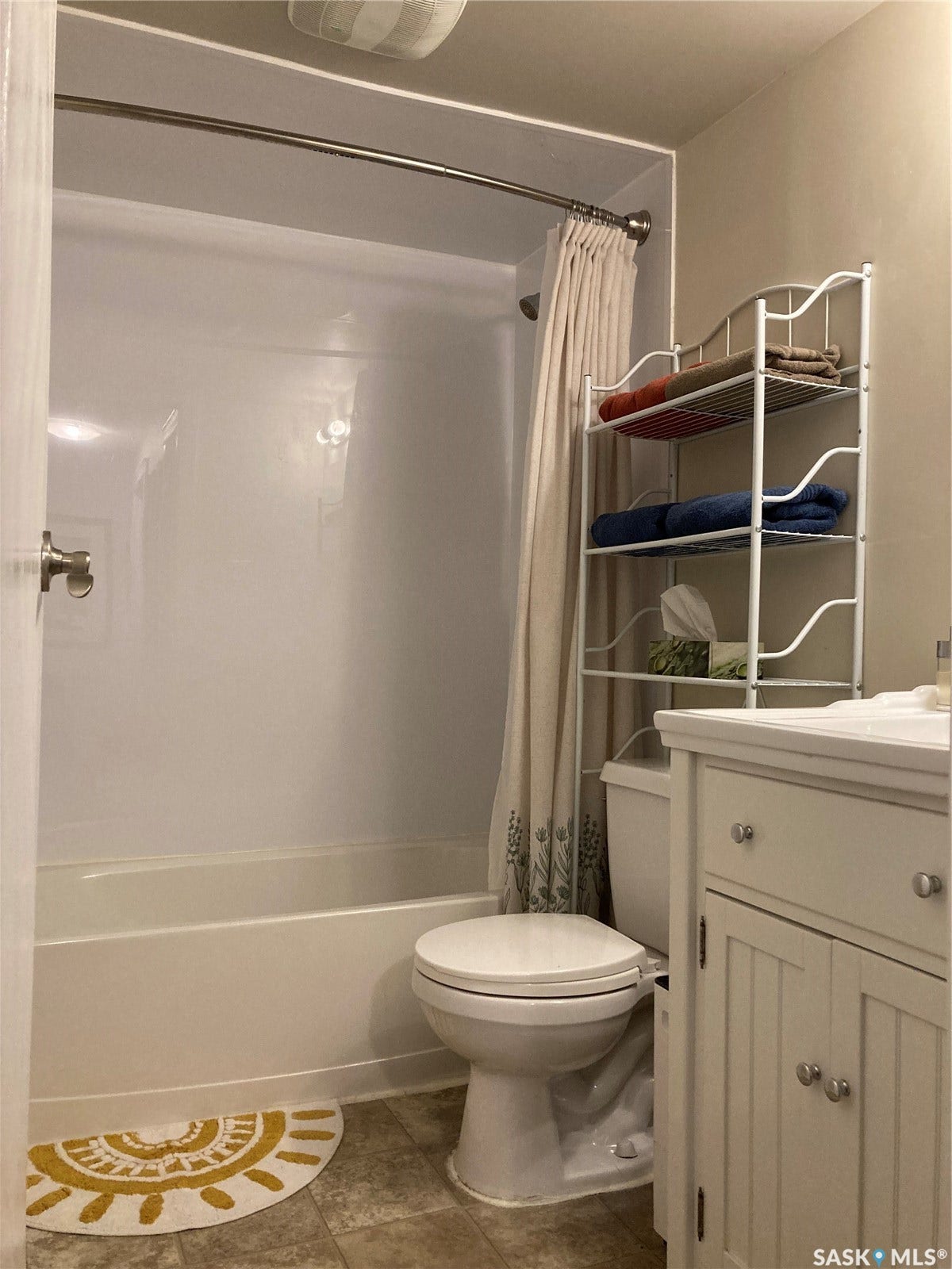 Bathroom with a white bathtub and shower combination, a toilet, a vanity with a white countertop and base cabinetry, and wood-finish flooring