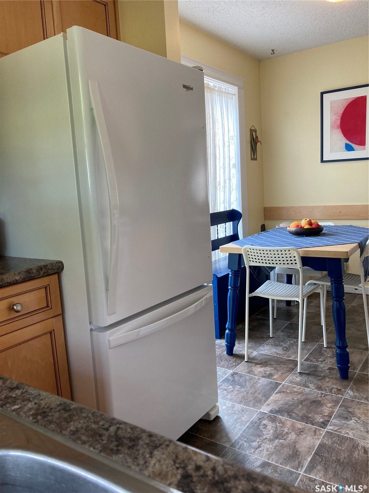 Kitchen featuring wood-finish cabinetry, a large refrigerator, and tiled flooring