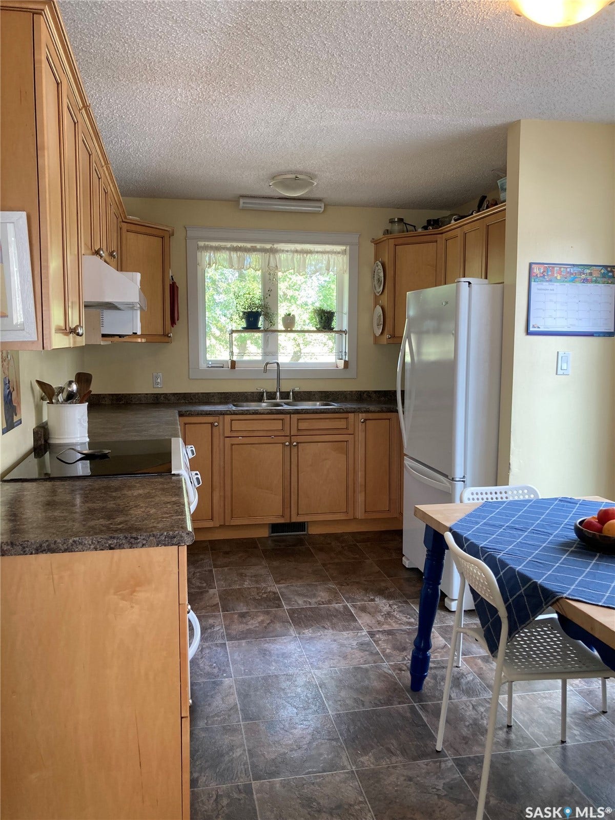 Kitchen with light wood-finish cabinetry, dark patterned countertops, and patterned floor tiles