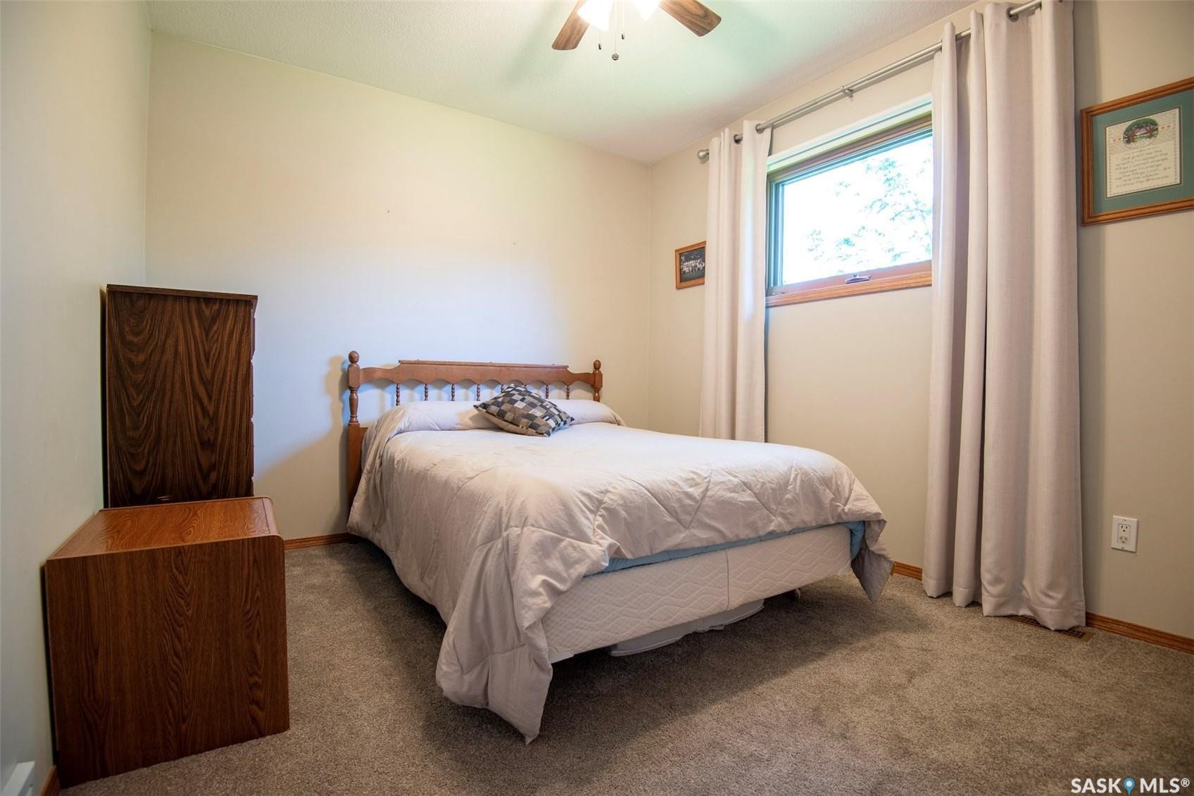 Carpeted flooring with a wood-finish ceiling fan and a window featuring a wood sill