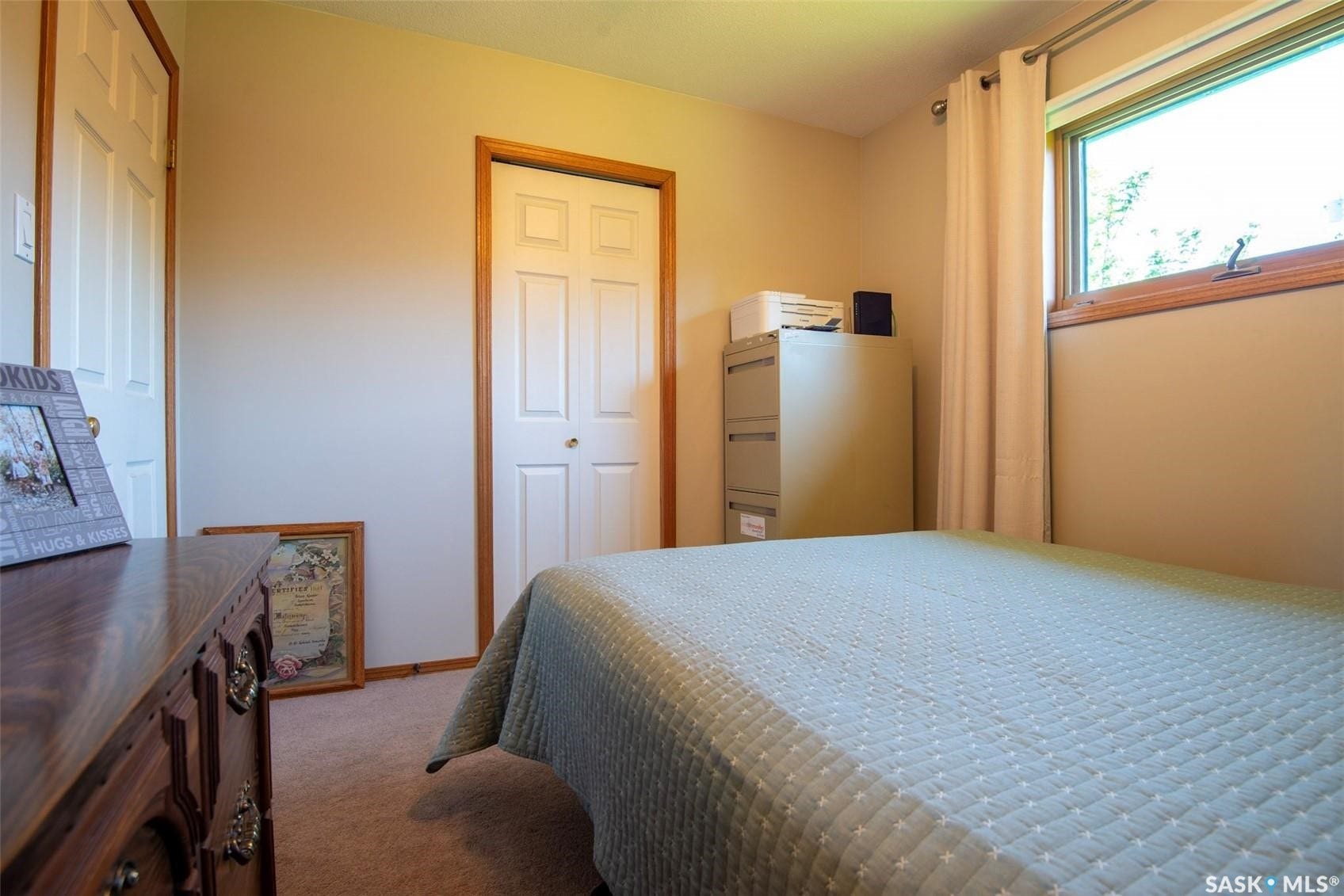 Carpeted flooring, window with wood trim, and a white bi-fold closet door