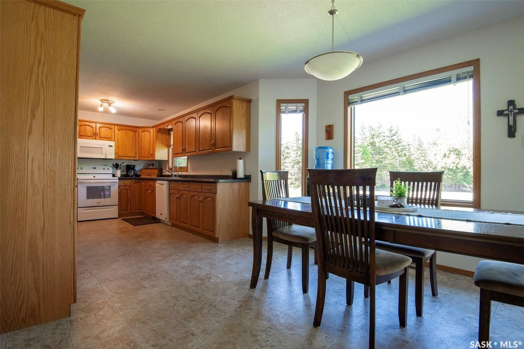 Kitchen featuring wood cabinetry, white appliances, and a dining area with a large window