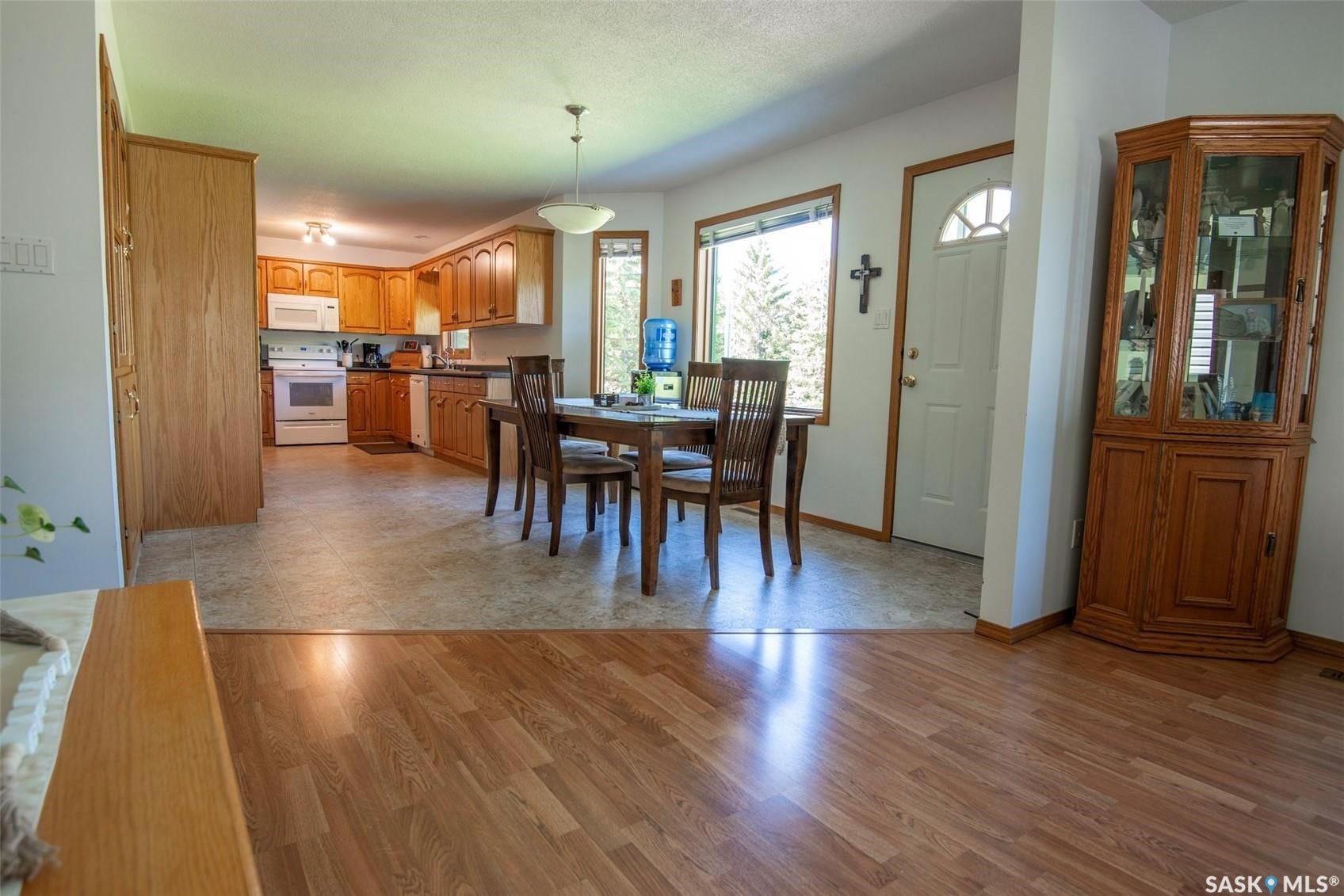Kitchen with wood-finish cabinetry, white appliances, and a dining area with a window
