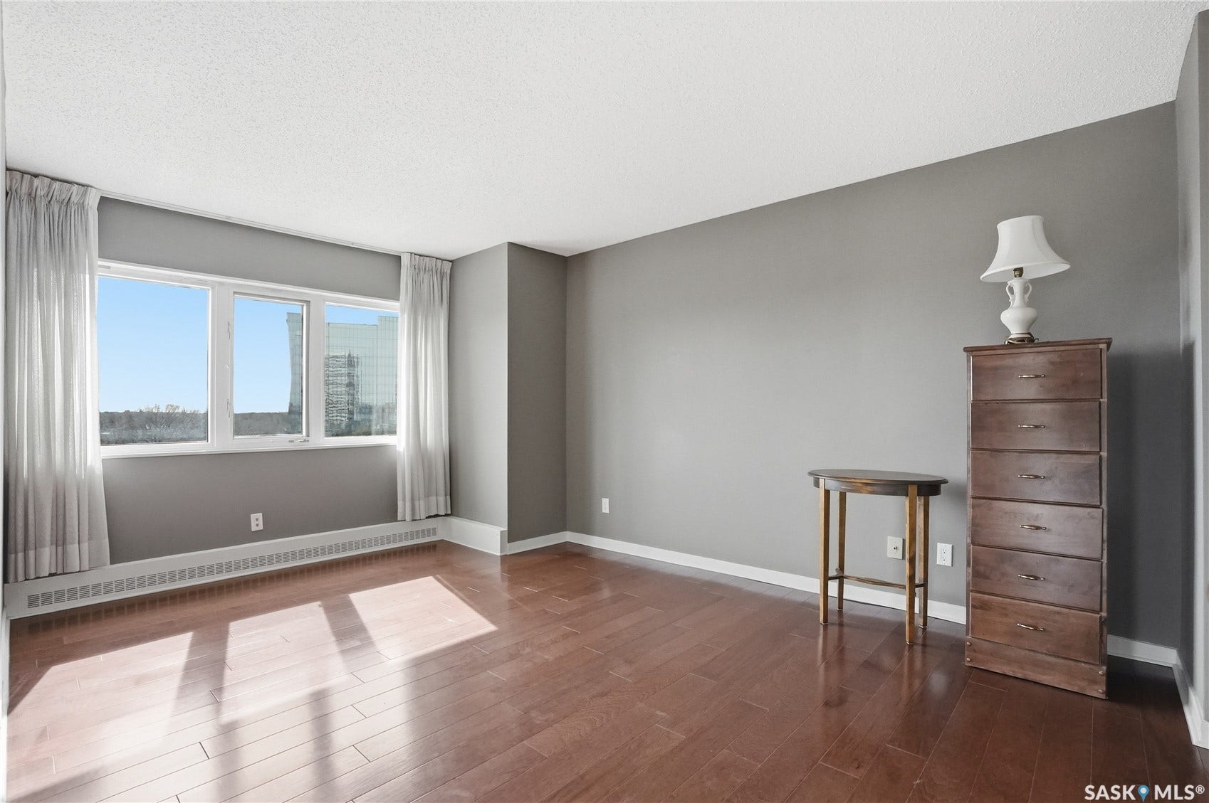Wood-finish flooring, crisp white trim, and a large window with sheers
