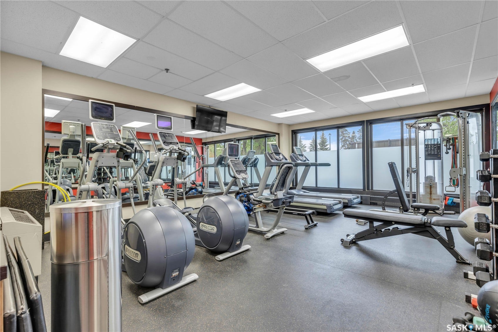 Fitness center featuring rubber flooring, mirrored walls, and large windows