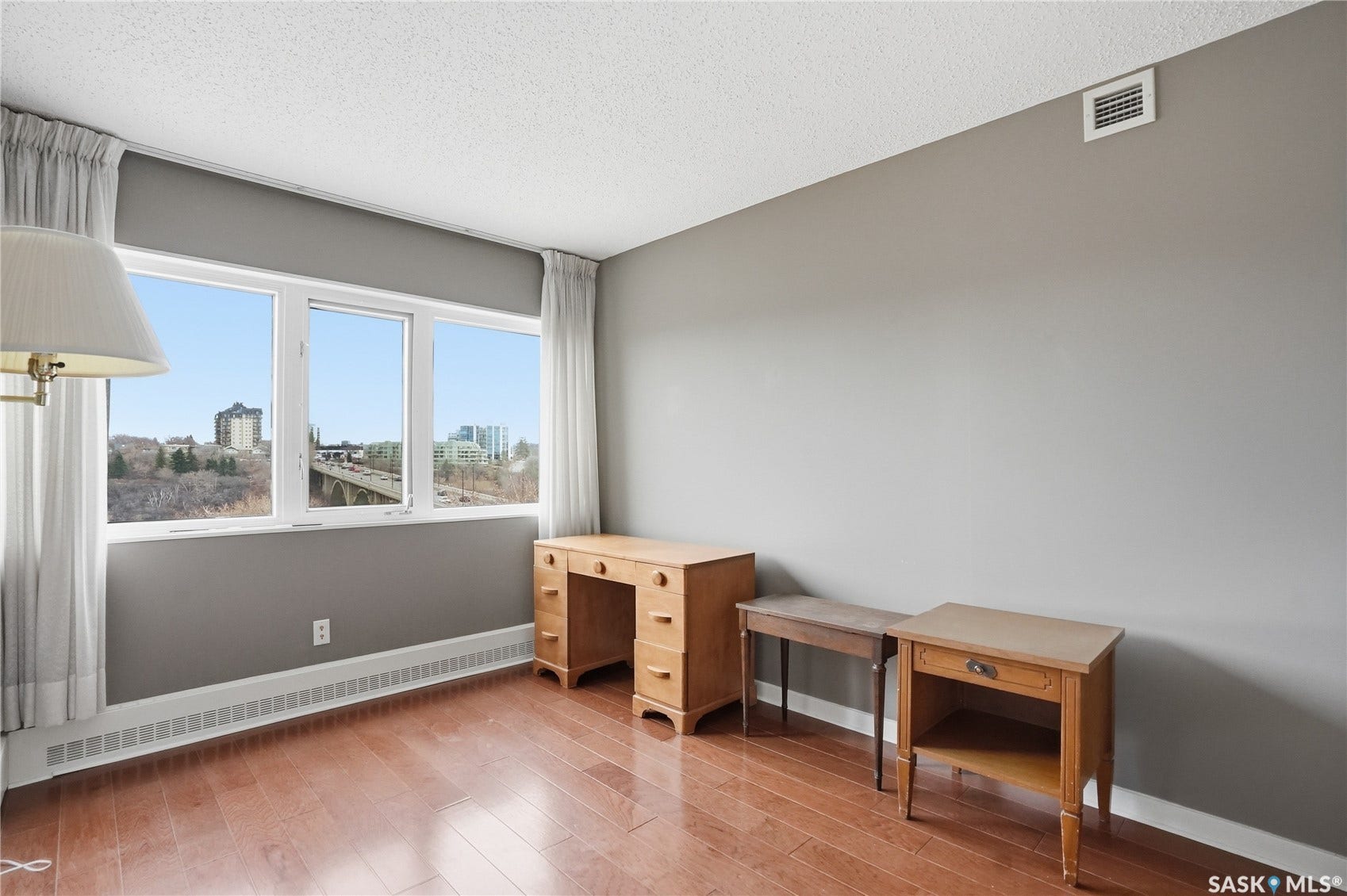 Hardwood flooring throughout, large picture windows, white window frames, and grey wall color