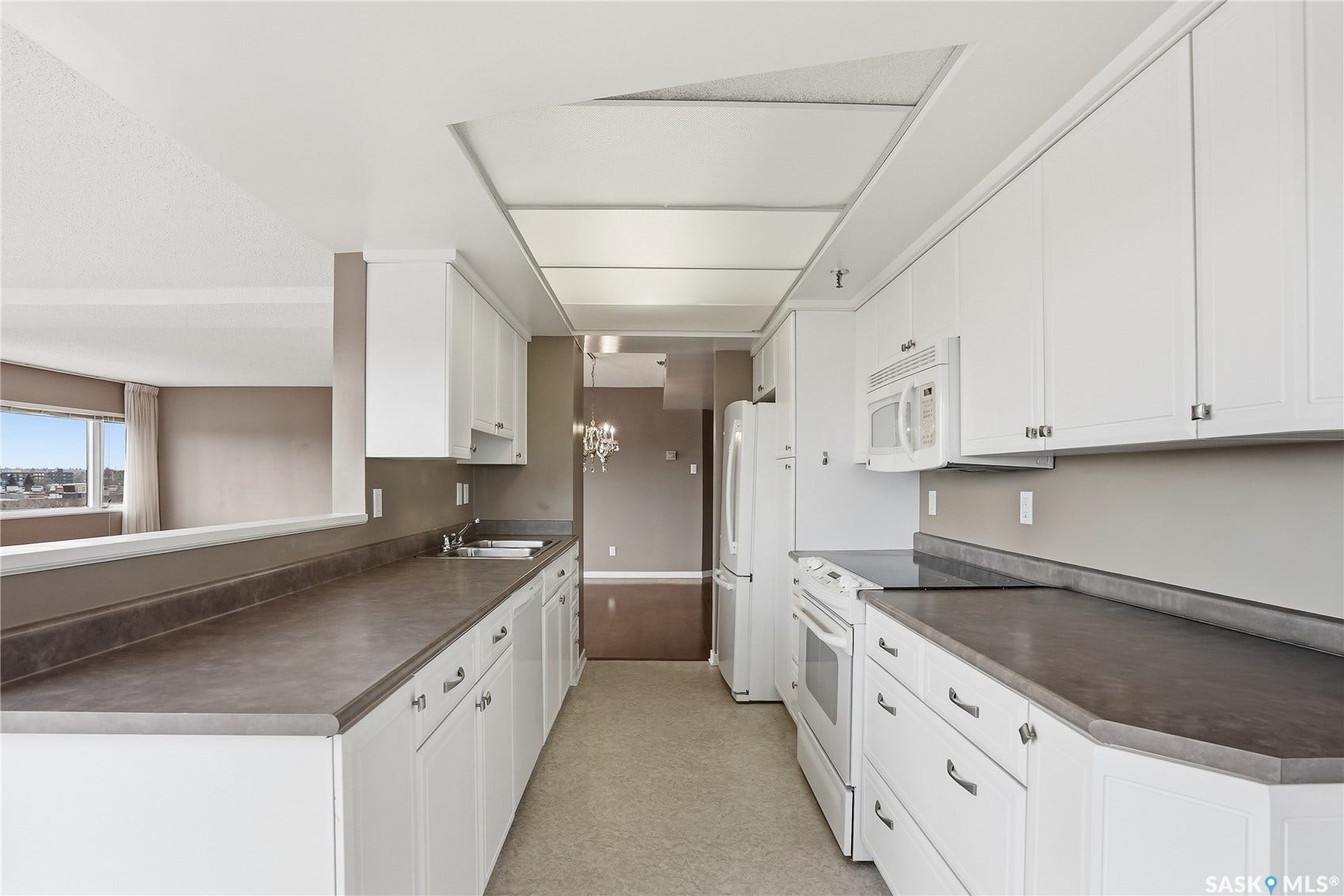 White cabinetry with brushed nickel hardware, integrated double-basin sink, built-in microwave, and a flat-top electric range