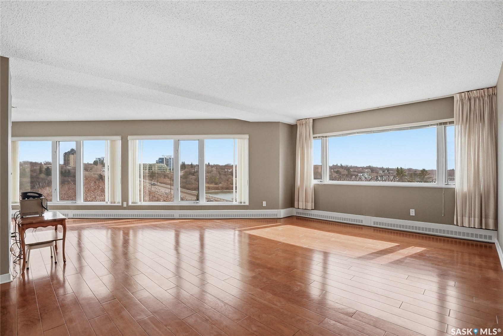 Expansive living area featuring wood-finish flooring, numerous large windows, and neutral wall tones