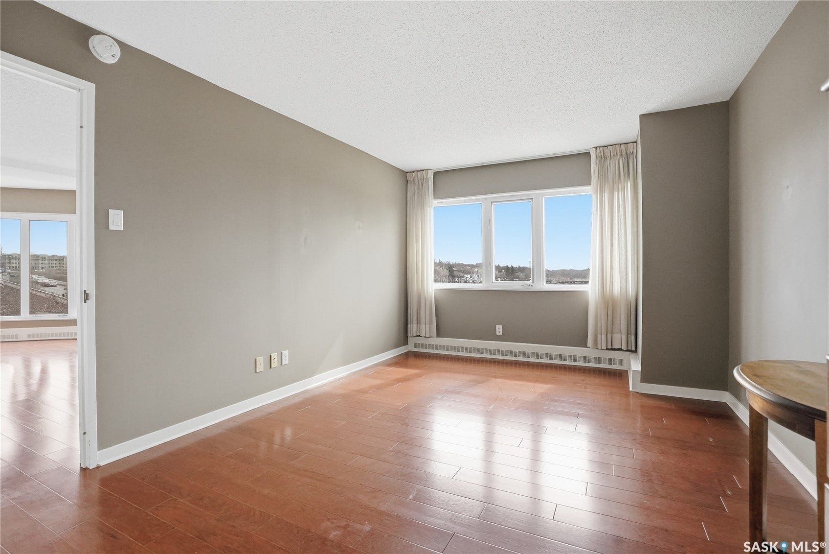 Hardwood-finish flooring, light grey wall paint, white trim, and white window coverings