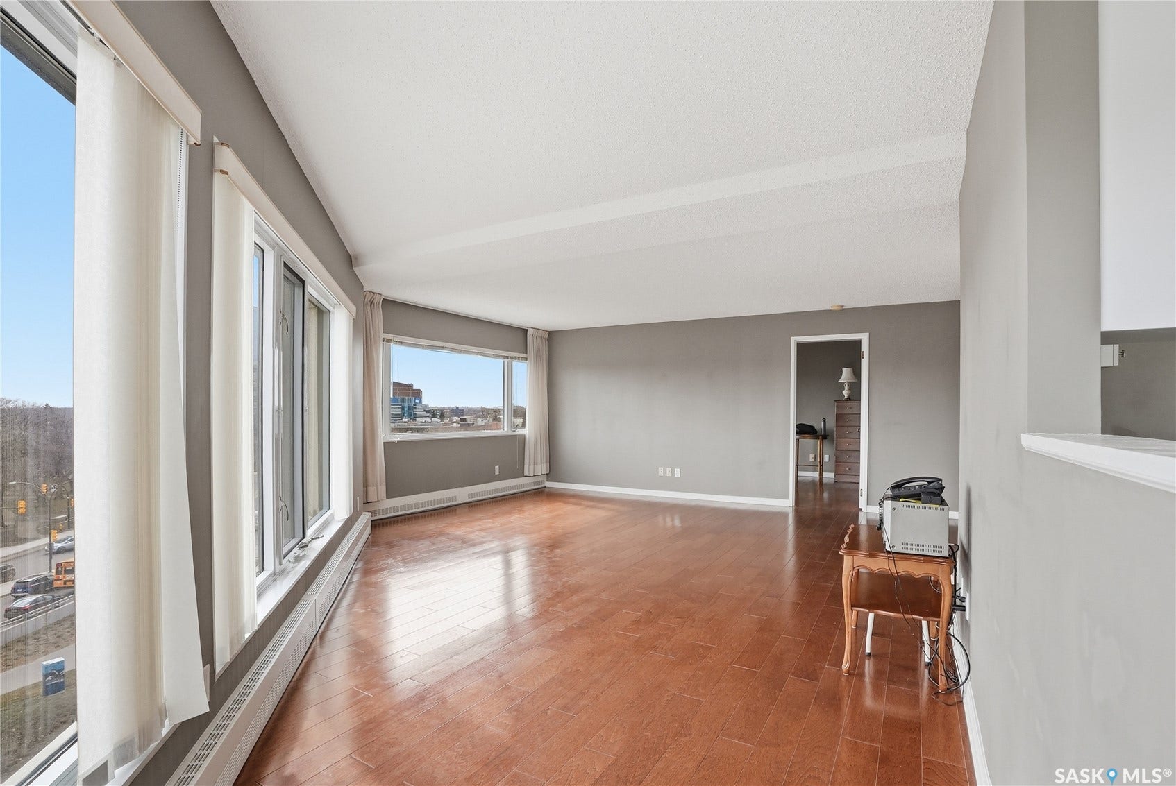Hardwood-finish flooring, light gray wall paint, white ceiling, and large windows providing ample natural light