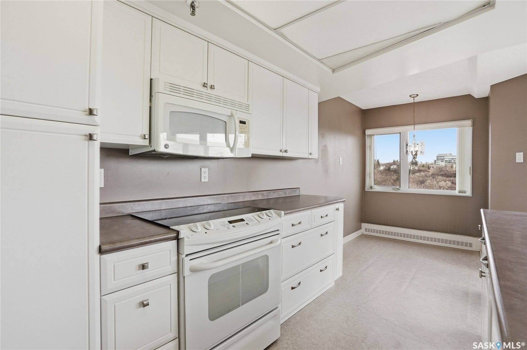 Kitchen featuring white cabinetry, a built-in microwave, an electric range, and a window