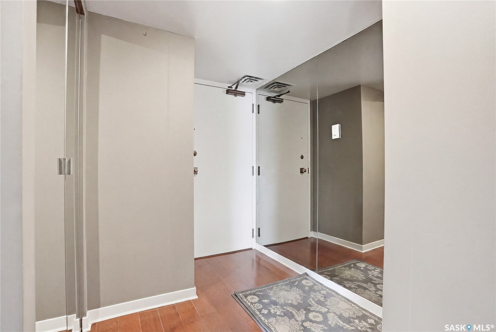 Full-height mirrored wall, wood-finish flooring, and white trim