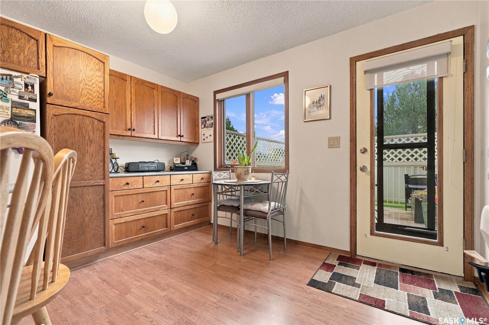 Wood-finish flooring, ample wood cabinetry, a large window, and a glass-paneled door