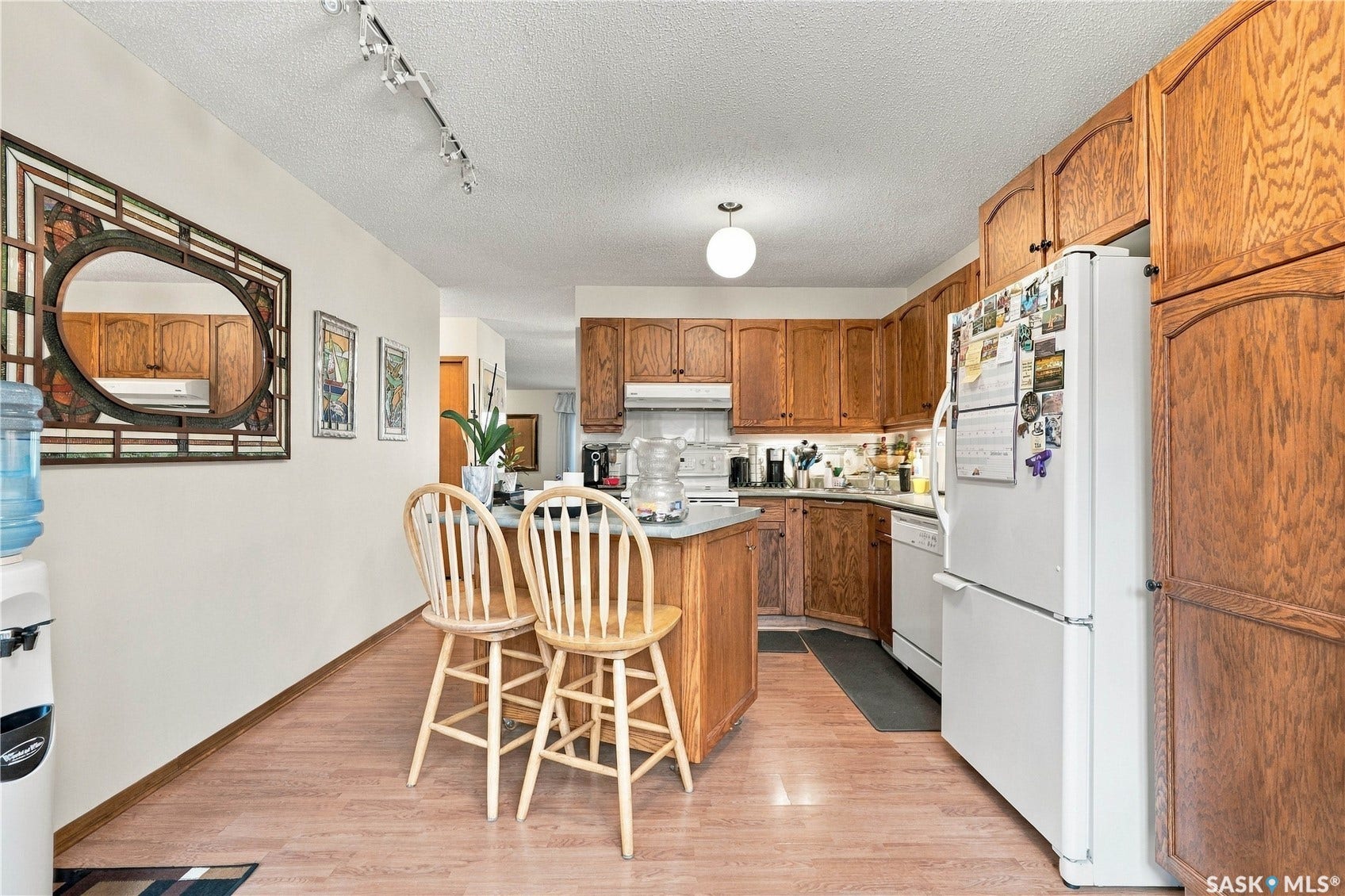 Wood-finish flooring throughout, track lighting, and a kitchen island with seating