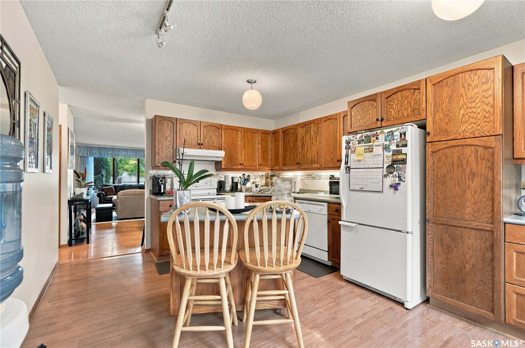 Kitchen featuring wood-finish flooring, wood cabinetry, white appliances, and a central island