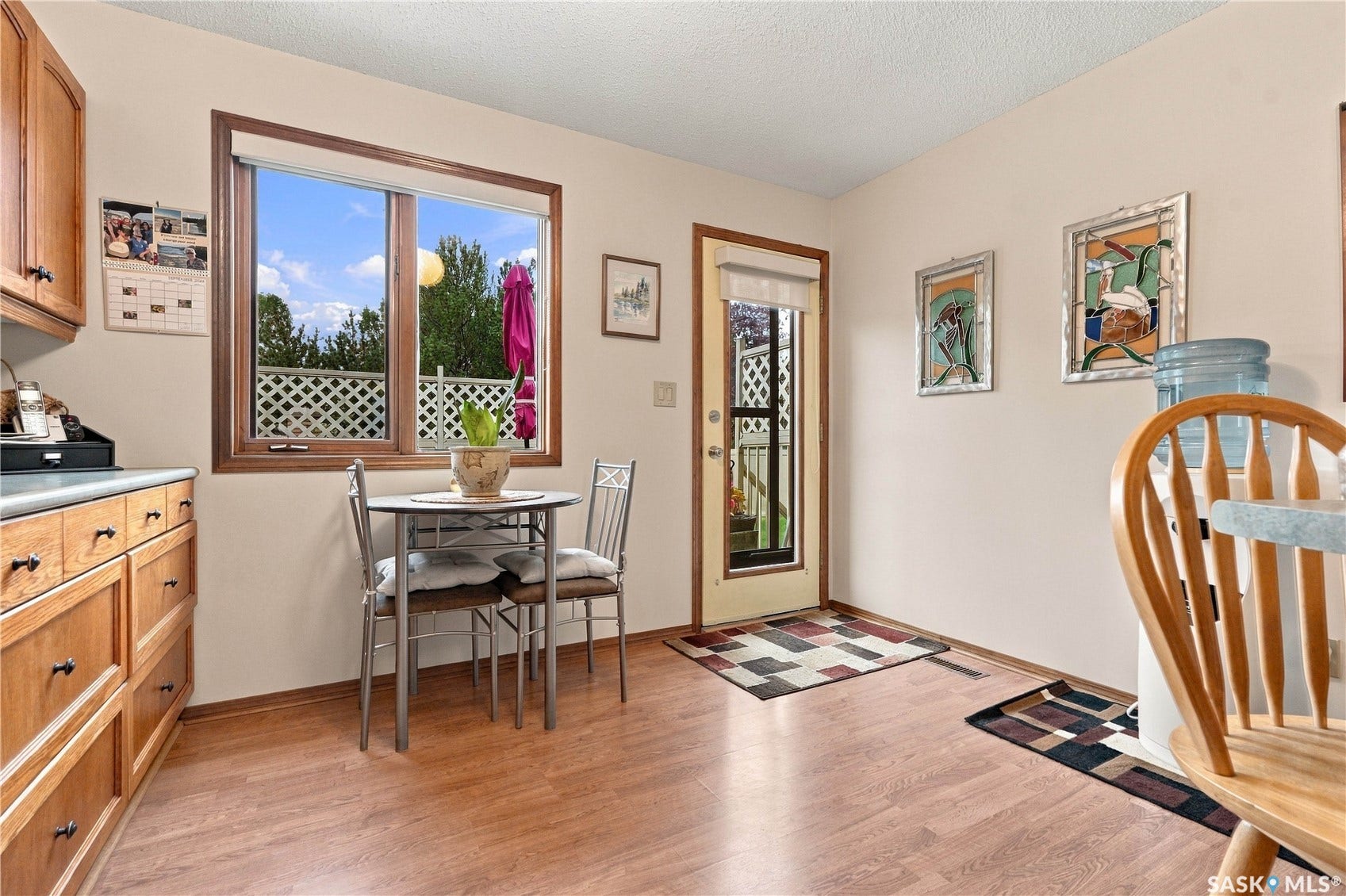 Wood-finish flooring throughout, light wood-tone cabinetry, and a full-light exterior door