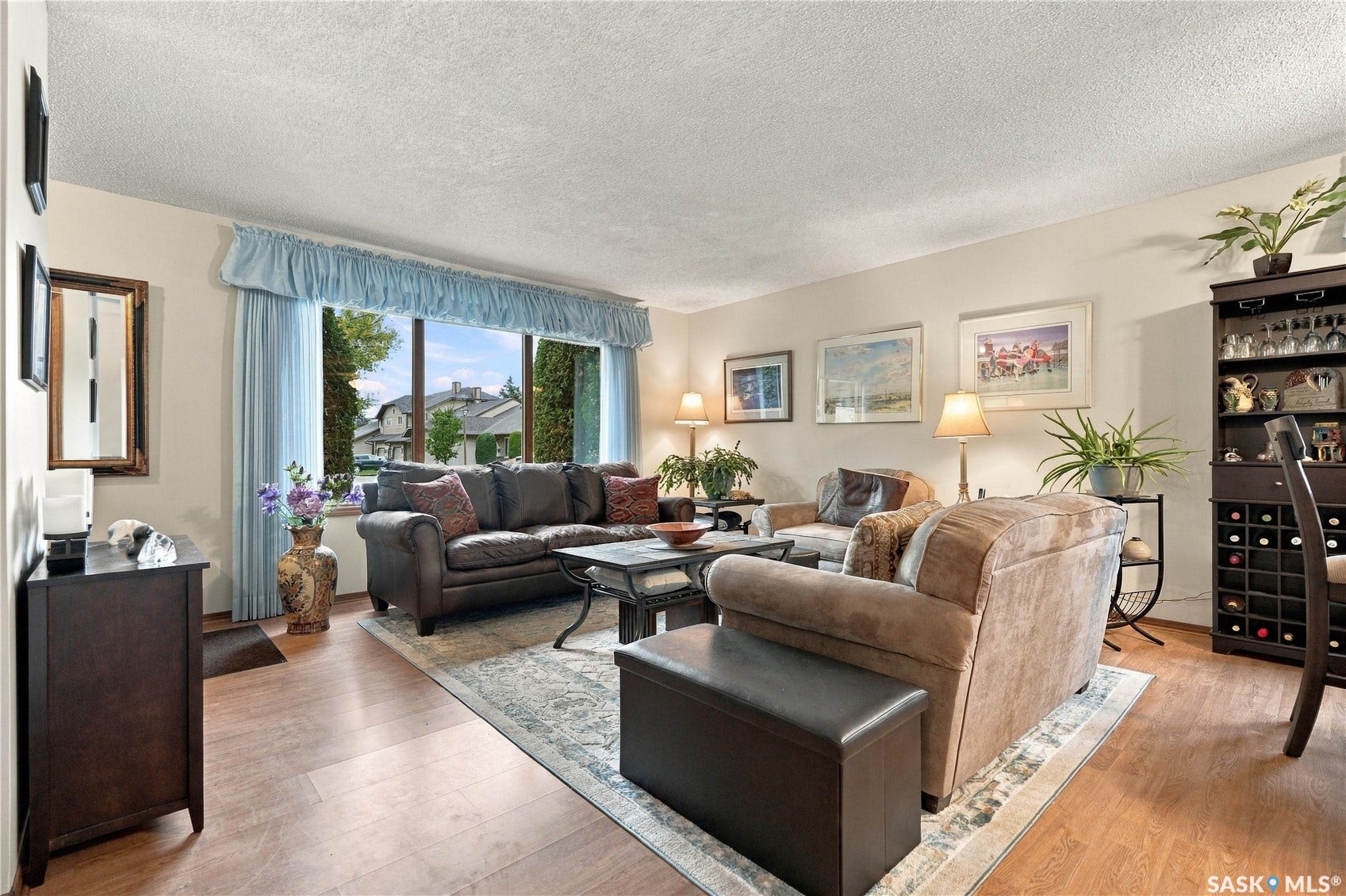 Hardwood-style flooring, large picture window, built-in shelving, and neutral wall tones