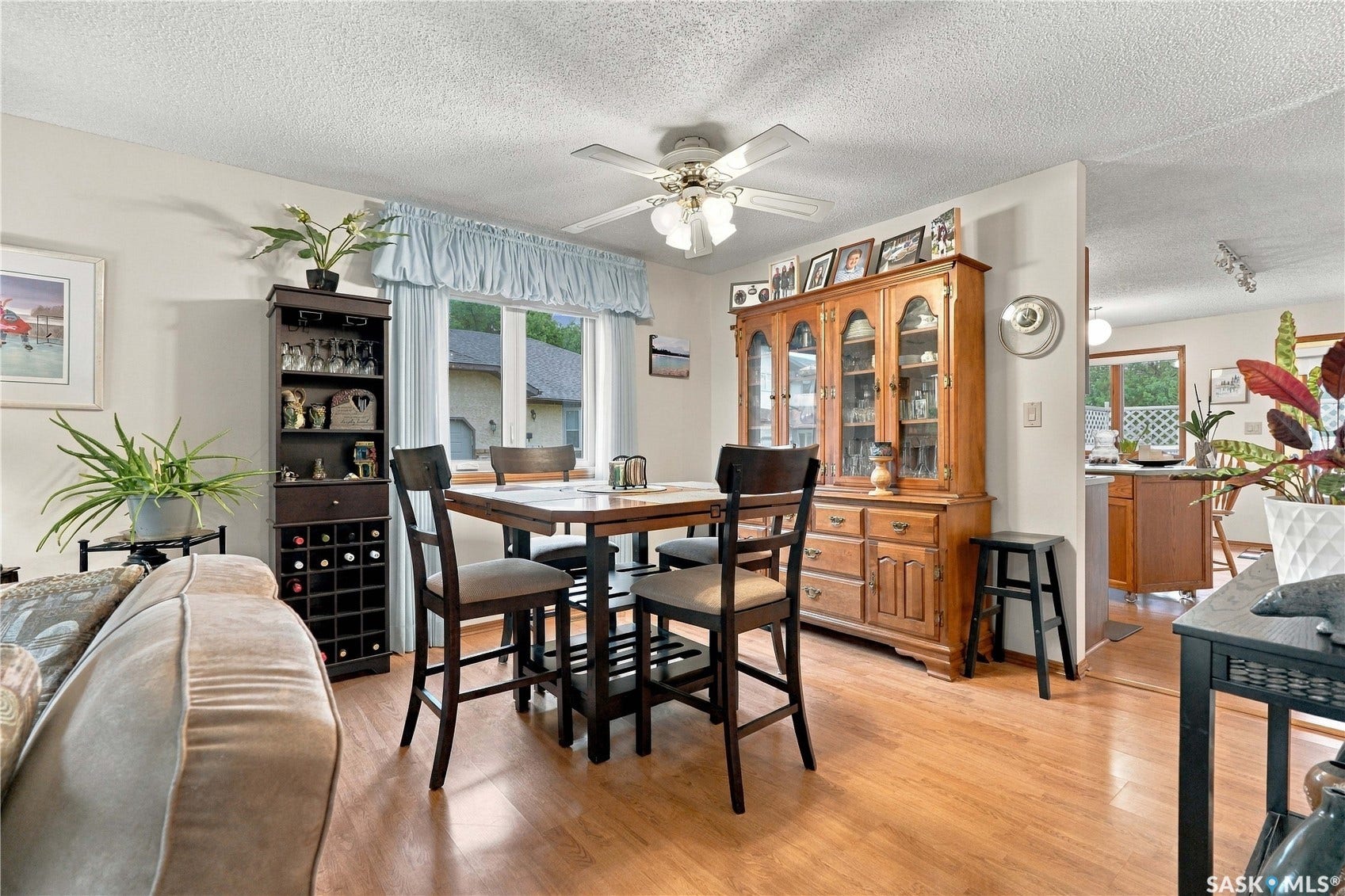Hardwood-finish flooring, ceiling fan with integrated lighting, built-in wine storage, built-in display cabinet, and a window providing natural light