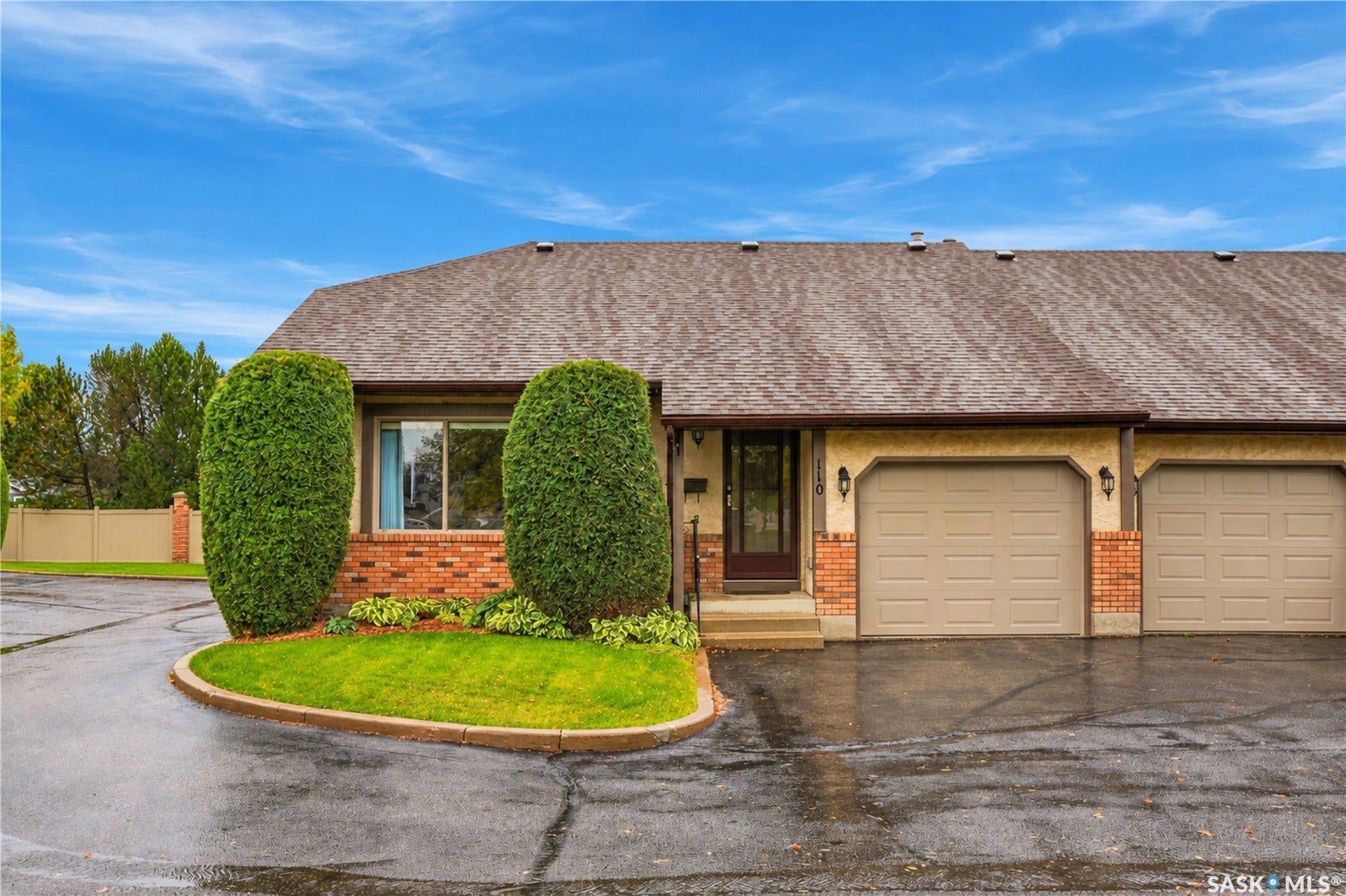 Brick and stucco exterior with multiple garage bays, a prominent entry door, and a manicured landscape bed